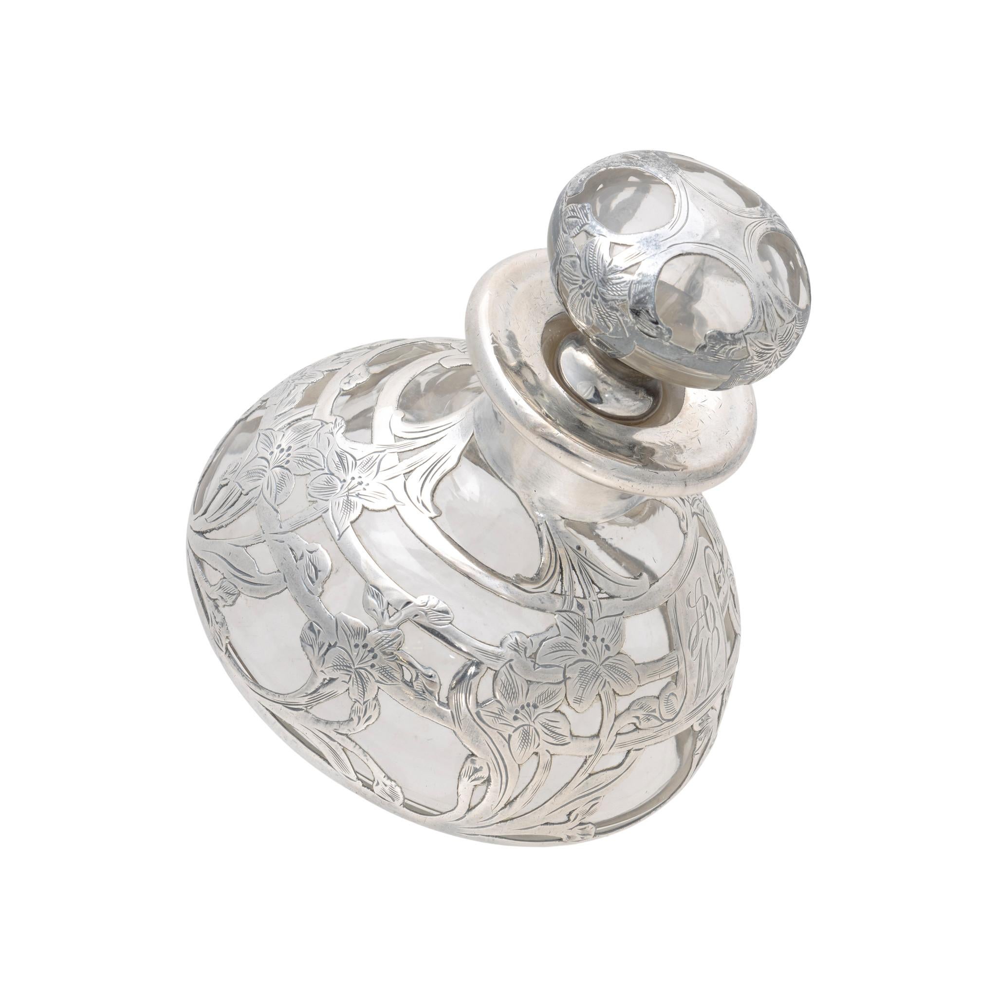 Alvin silver overlay glass perfume bottle. With clear glass and art nouveau style silverwork, featuring 8 bouquets of daffodil or narcissus flowers with complementary design on stopper. Center has monogrammed letters 