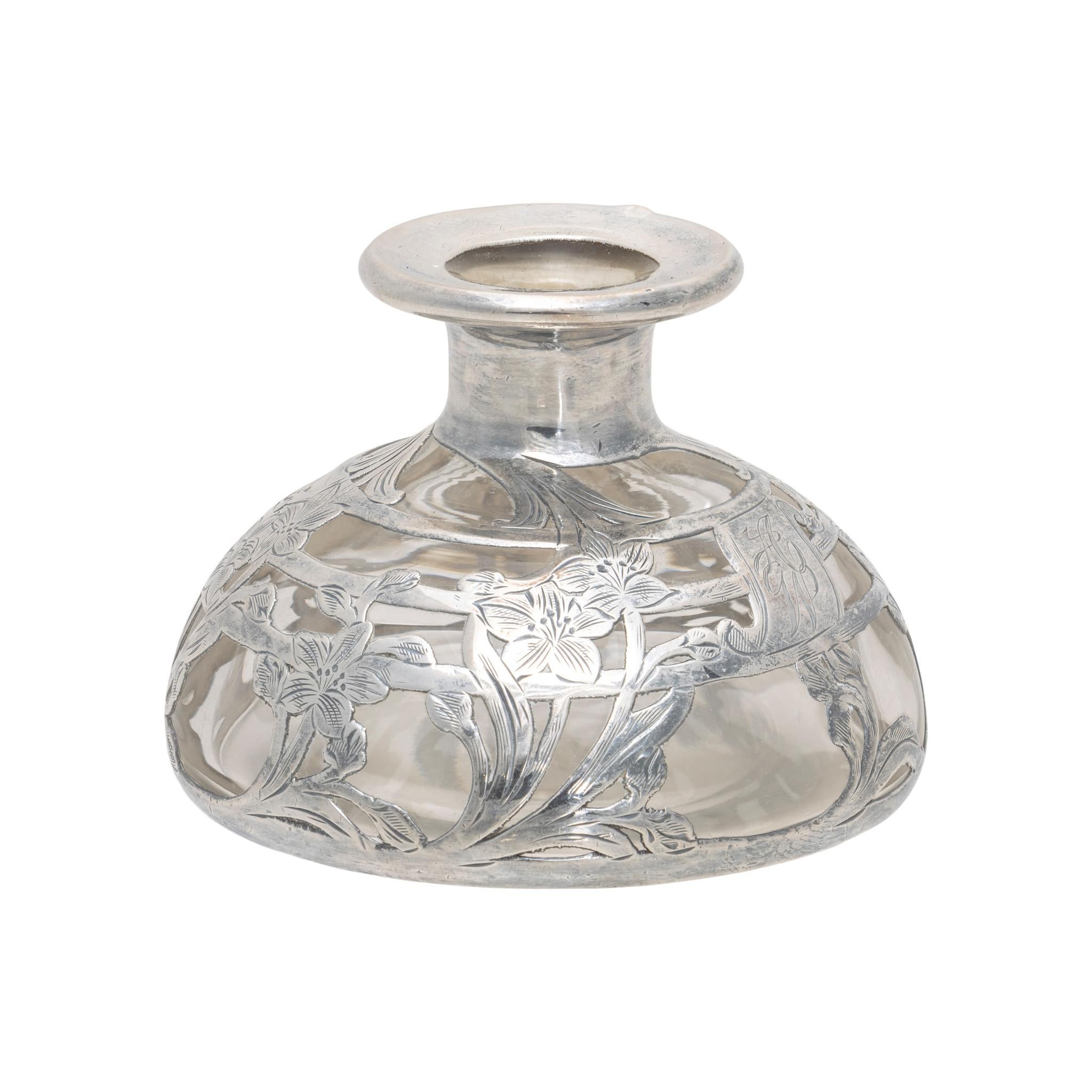 Alvin silver overlay glass perfume bottle. With clear glass and art nouveau style silverwork, featuring 7 bouquets of daffodil or narcissus flowers with complementary design on stopper. Center has monogrammed letters 
