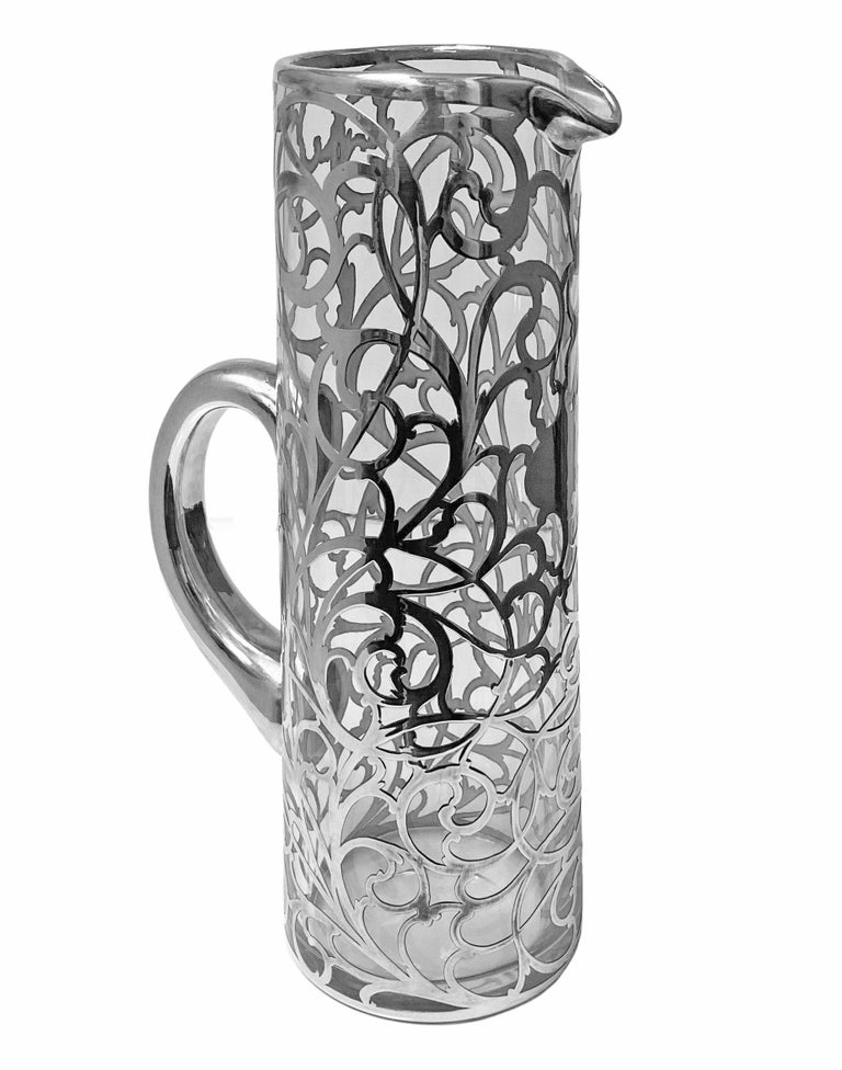 Alvin sterling overlay clear glass jug pitcher, c. 1900. Large size tapered cylindrical, with thick applied sterling silver overlay, reticulated and engraved scrolling vine, central vacant cartouche. Rubbed Alvin Corp marks to base rim 999/1000 Fine