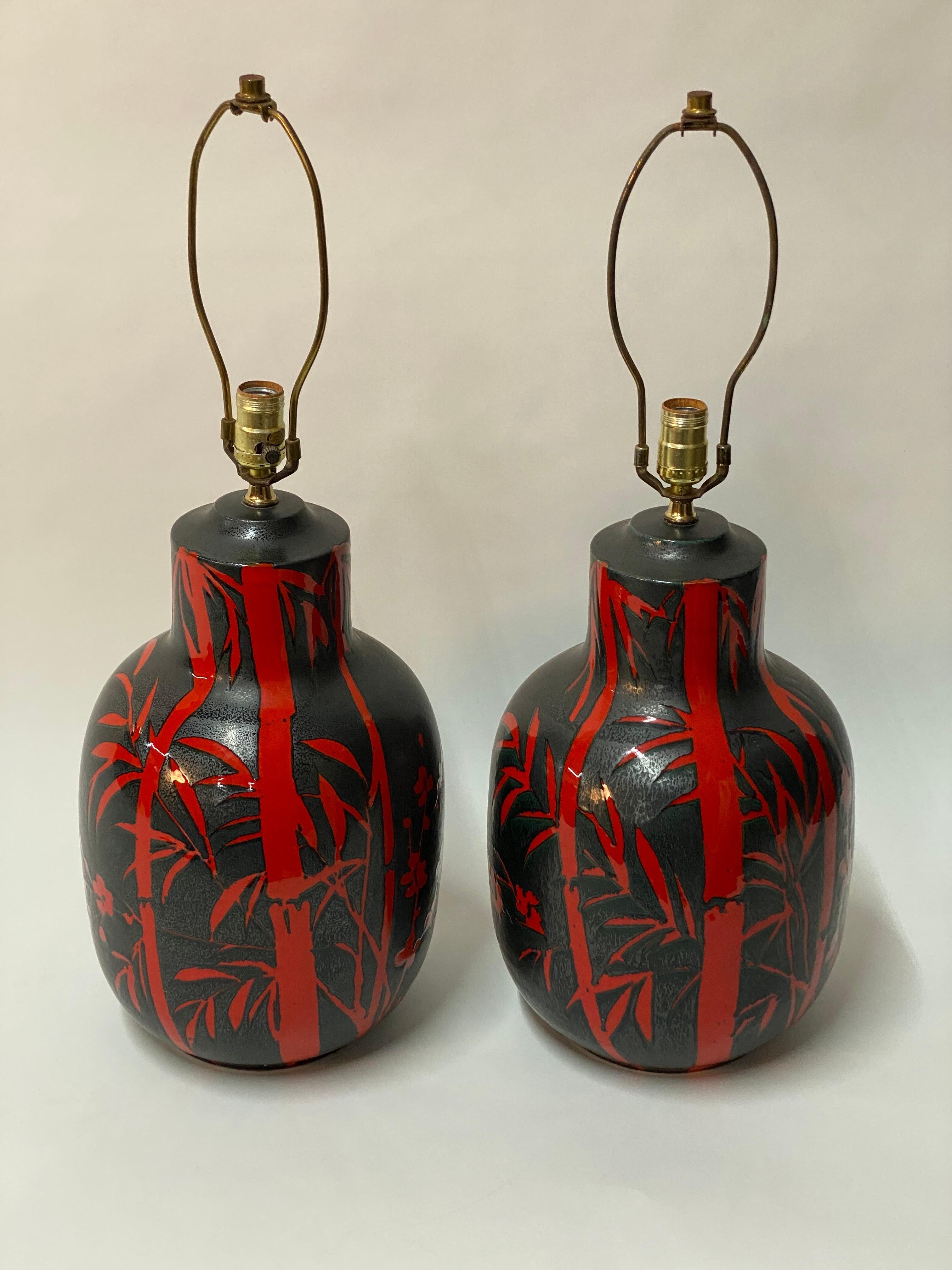 Stunning pair of Alvino Bagni Bitossi Italian pottery table lamps. Decorated and glazed in a speckled gunmetal charcoal gray/black and vermillion. The decor in red is bamboo, butterflies and peach blossom type flowers. Photos do not do the