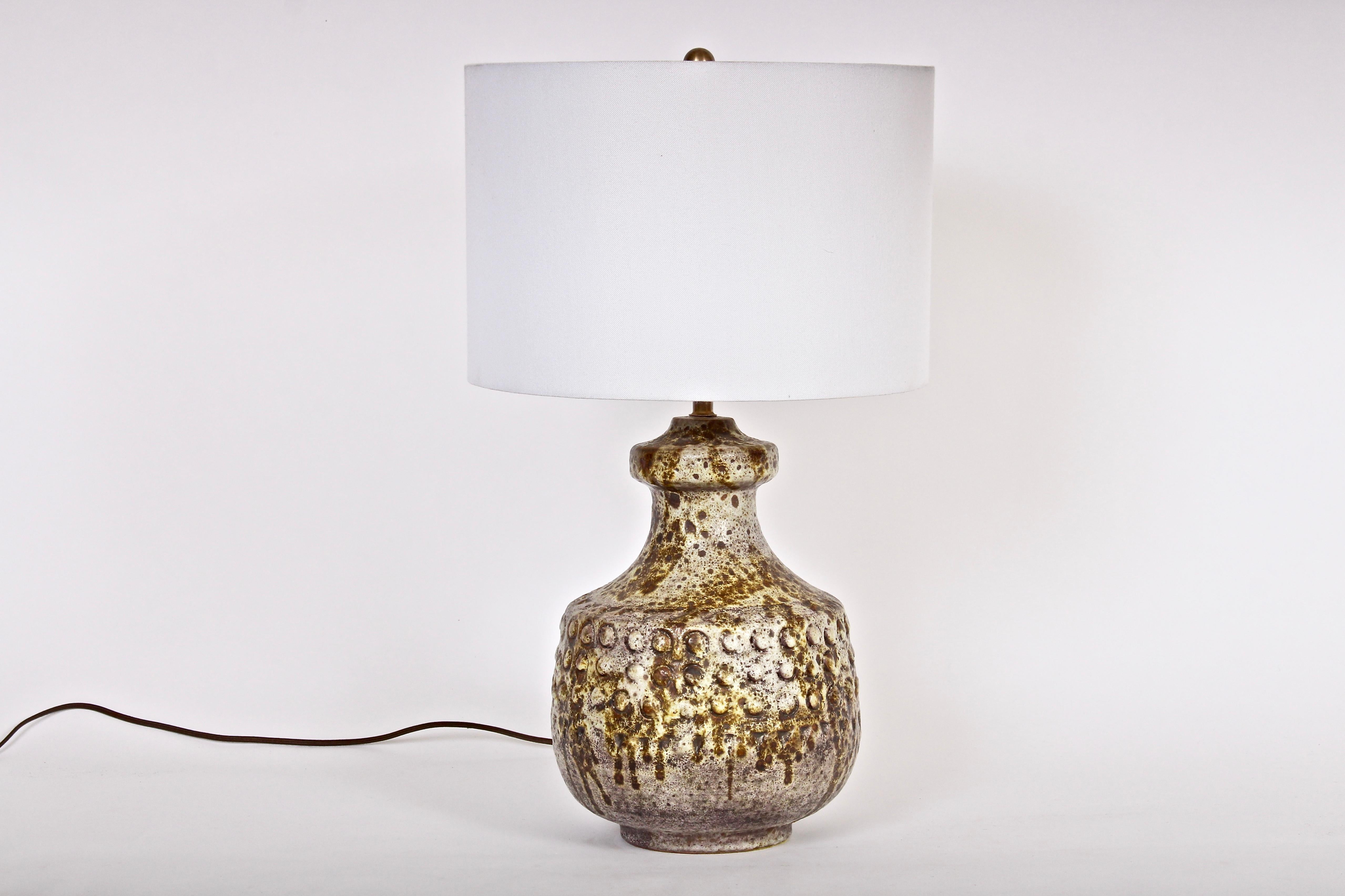 Italian Modern Alvino Bagni textured bright earthen drip glazed ceramic bedside lamp. Featuring a three dimensional handcrafted squat body with raised button accents. With speckled and reflective coloration in beige, white, brown, coffee and pale