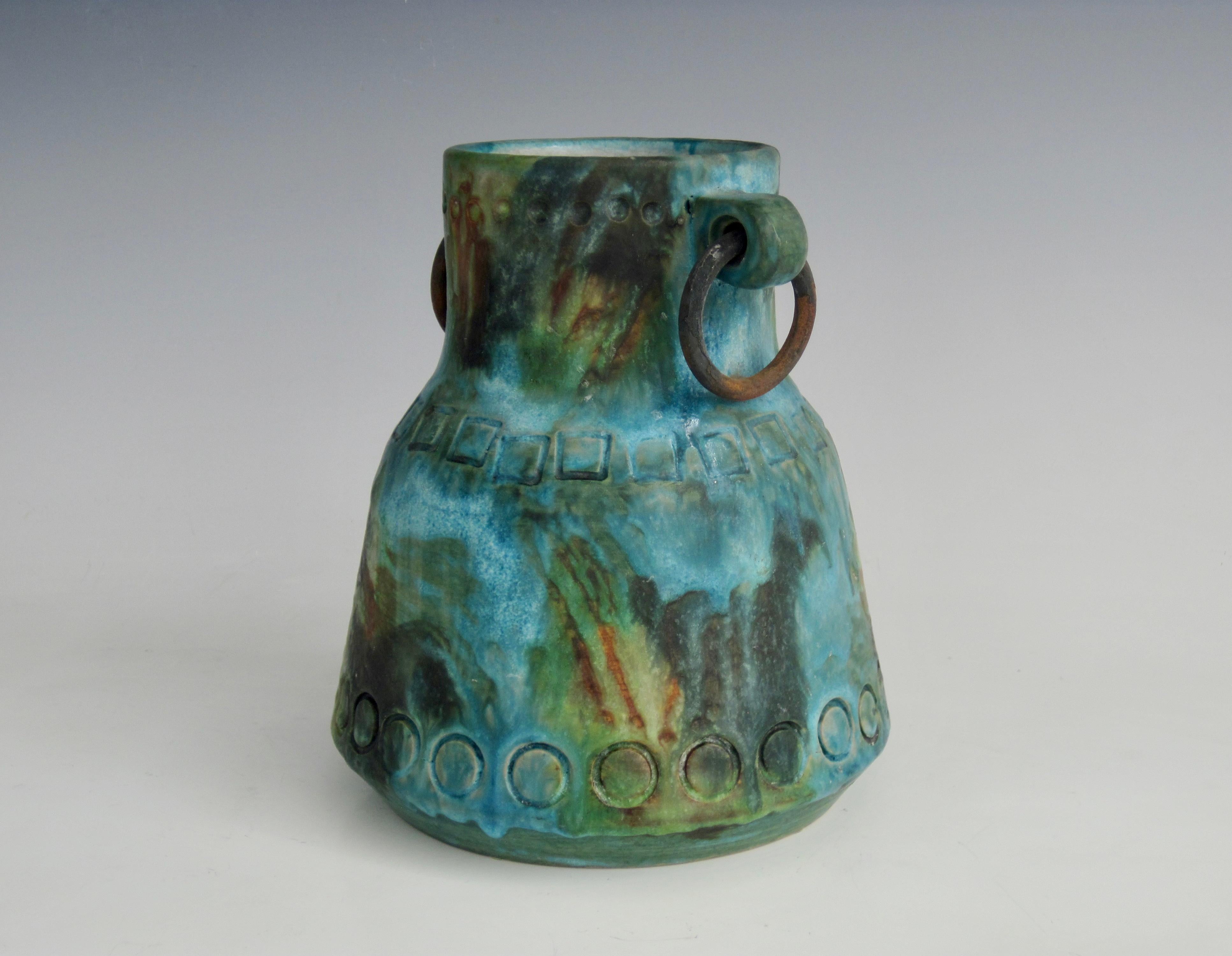 Alvino Bagni 's (1919-2000) handled vessel with brass rings from his Sea Garden Series. This series made up of turquoise, blue, green, yellow, brown, and black often had surface impressions such as the circles and squares at the top, middle and near