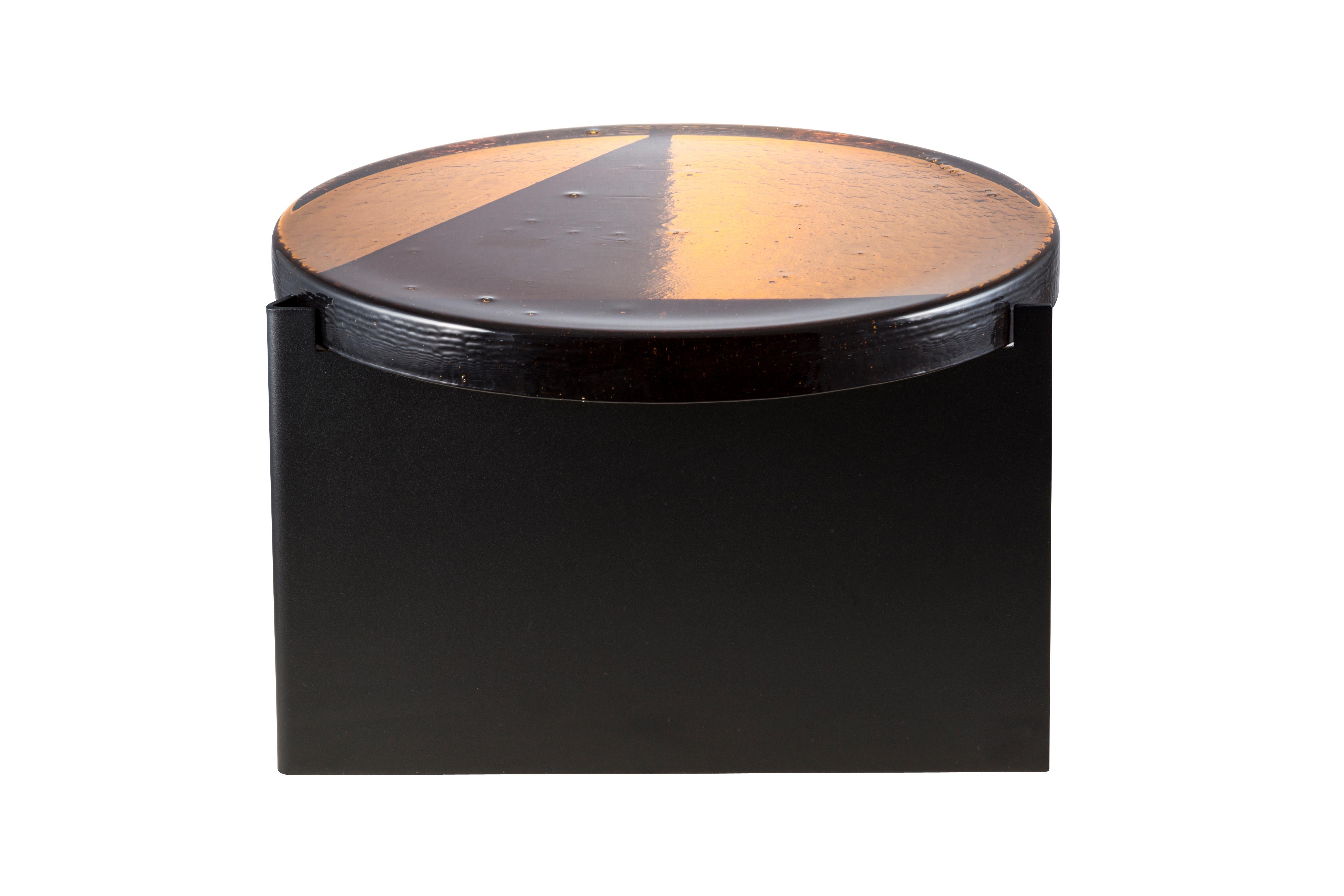 Alwa one big amber black coffee table by Pulpo
Dimensions: D56 x H35 cm
Materials: casted glass; powder coated steel 

Also available in different finishes. 

Normally, glass is regarded as being lightweight with sharp edges. In contrast,