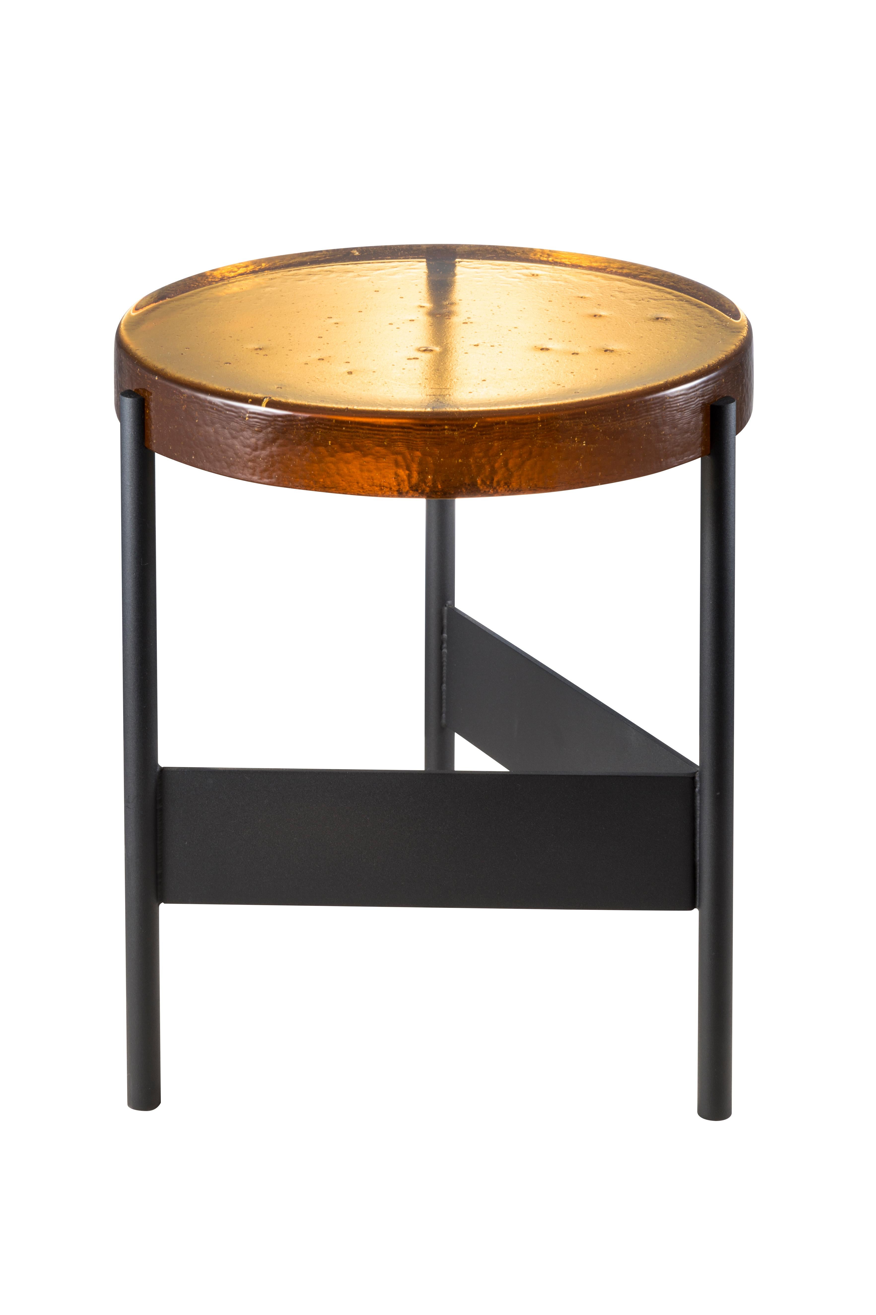 Alwa two amber black side table by Pulpo
Dimensions: D38 x H44 cm
Materials: casted glass; powder coated steel 

Also available in different finishes. 

Normally, glass is regarded as being lightweight with sharp edges. In contrast, Sebastian