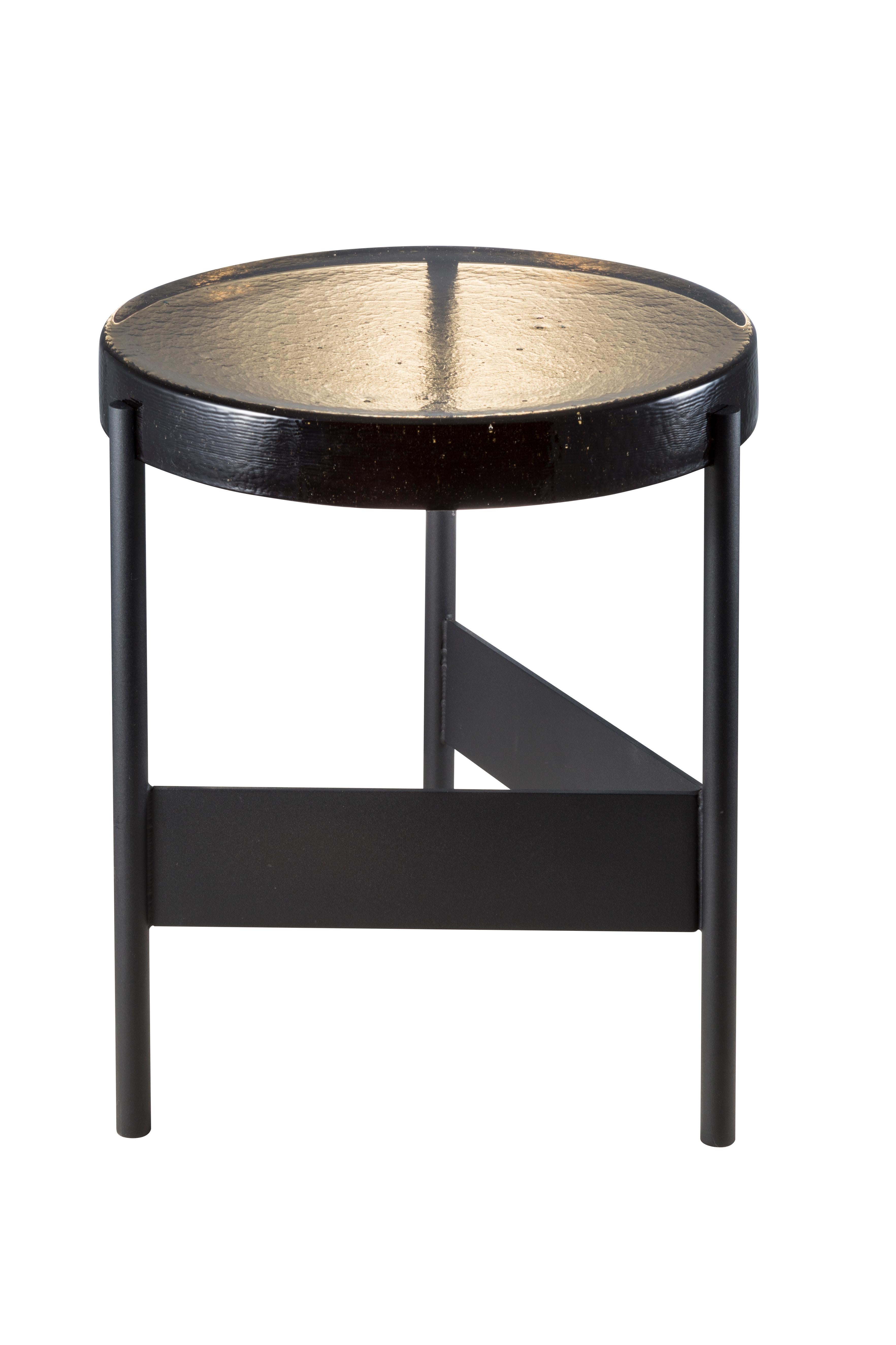 Alwa two smoky grey black side table by Pulpo
Dimensions: D 38 x H 44 cm
Materials: casted glass; powder coated steel 

Also available in different finishes.

Normally, glass is regarded as being lightweight with sharp edges. In contrast,