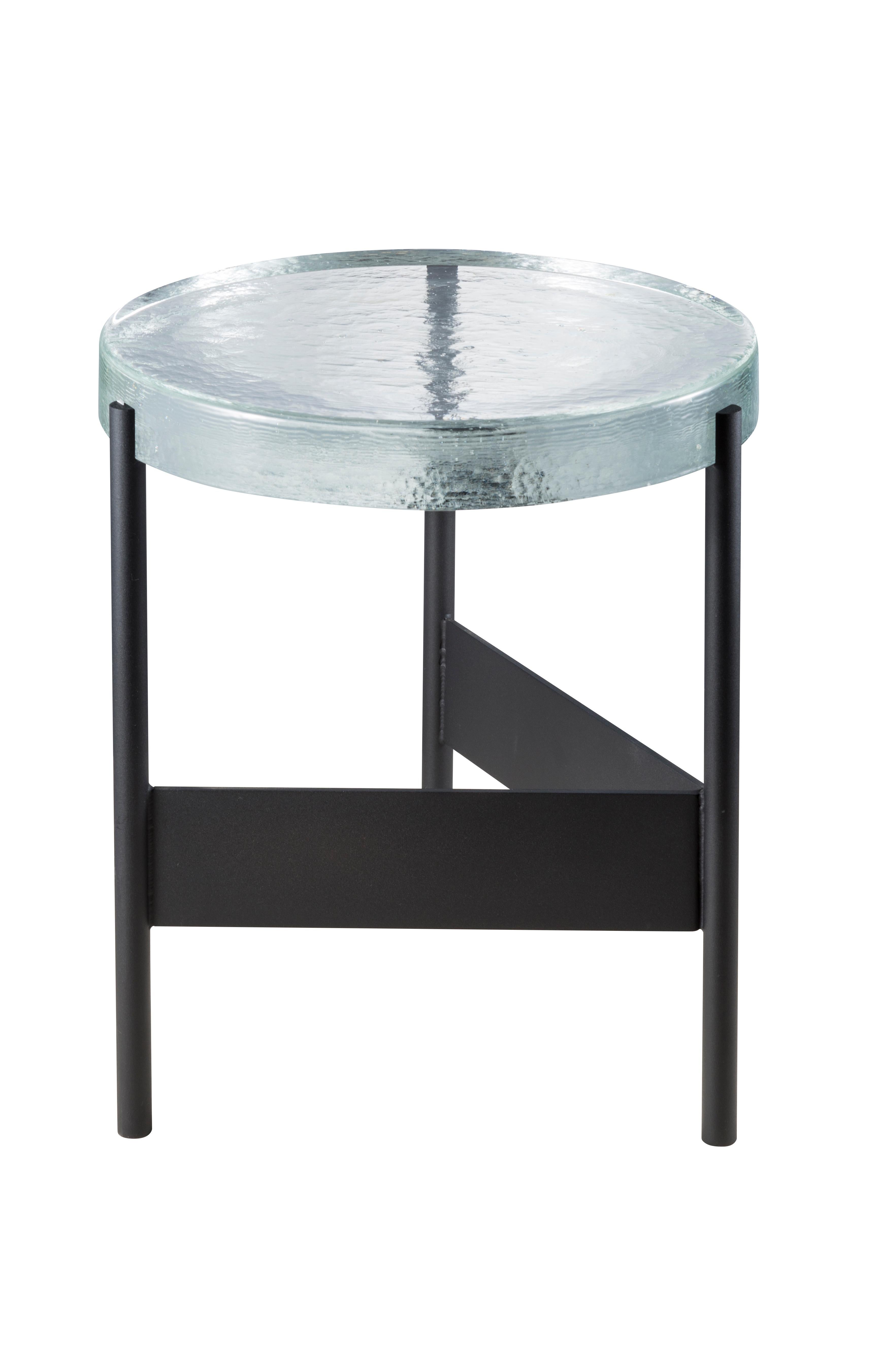 Alwa two transparent black side table by Pulpo
Dimensions: D38 x H44 cm
Materials: casted glass; powder coated steel 

Also available in different finishes.

Normally, glass is regarded as being lightweight with sharp edges. In contrast,