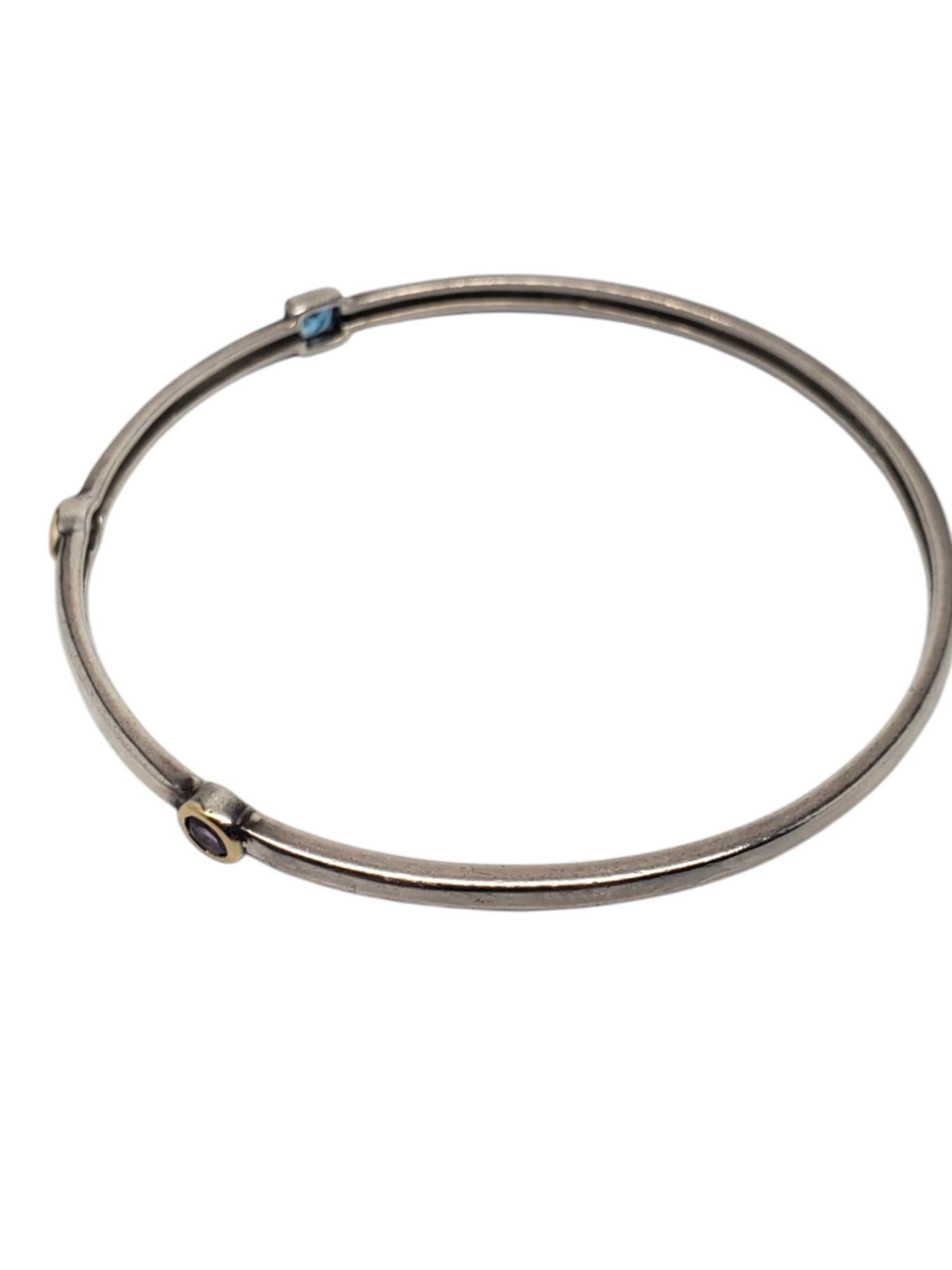 Alwand Vahan Sterling Silver & 14k Bezel Set Gemstone Bracelet-

This vintage bracelet features citrine, amethyst, & blue topaz gemstones bezel set in 14k. gold on a sterling silver bangle by Alwand Vahan.

Size: 8.5 in. around inside in