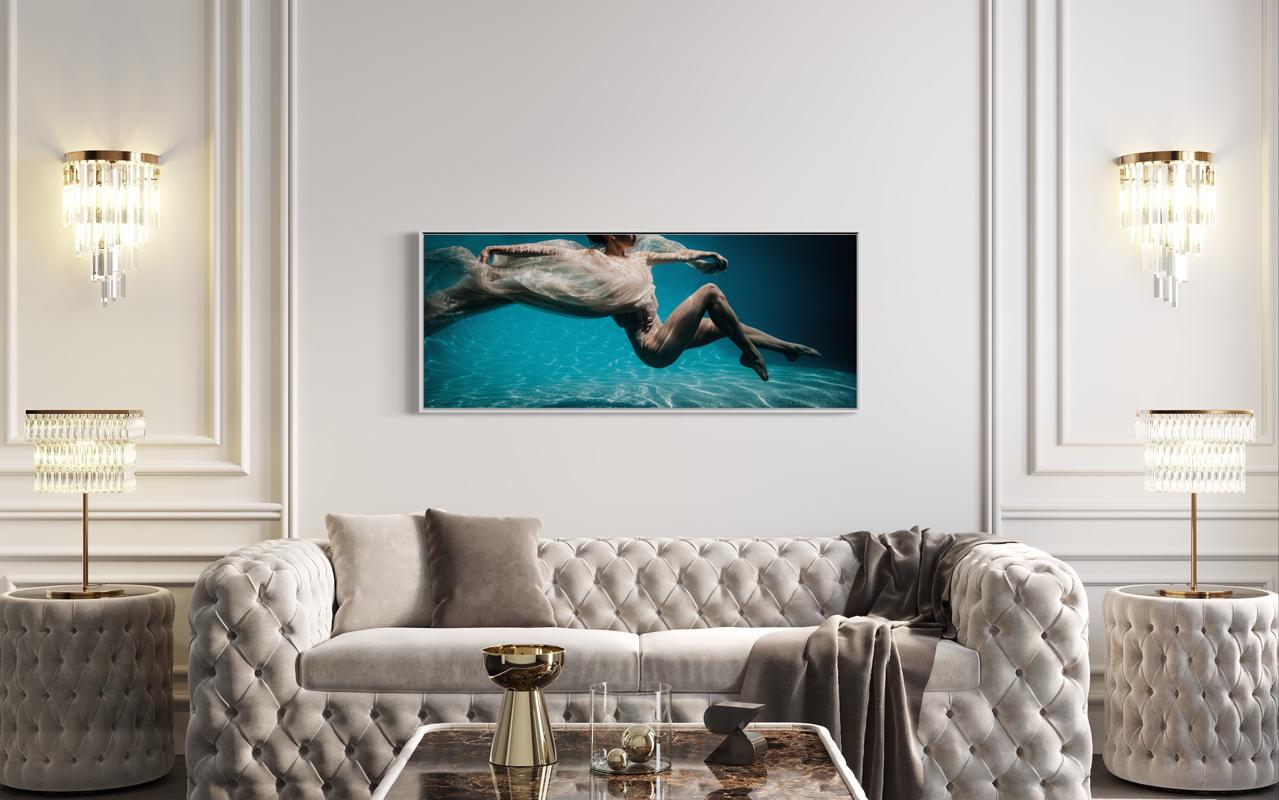Cette photographie figurative contemporaine en édition limitée d'Alyssa Fabrice capture une figure féminine, enveloppée dans un tissu léger et doux, flottant sous la surface d'une eau bleue dans une pose de danseuse. 