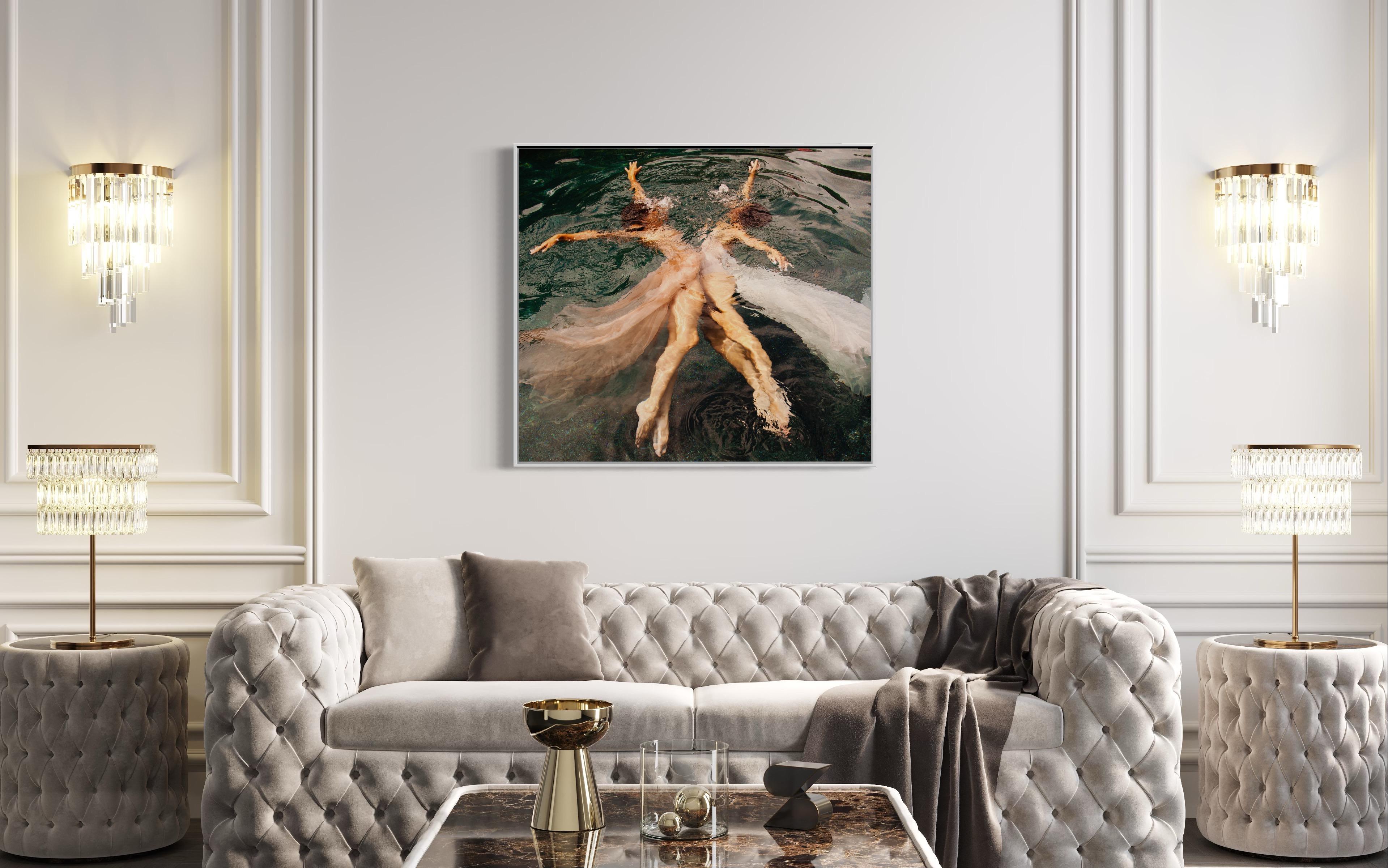 This contemporary figural limited edition photograph by Alyssa Fortin features a view from above the surface of water, with two female figures posed in dancer-like poses. Facing one another, they extend their arms and legs with blush and white