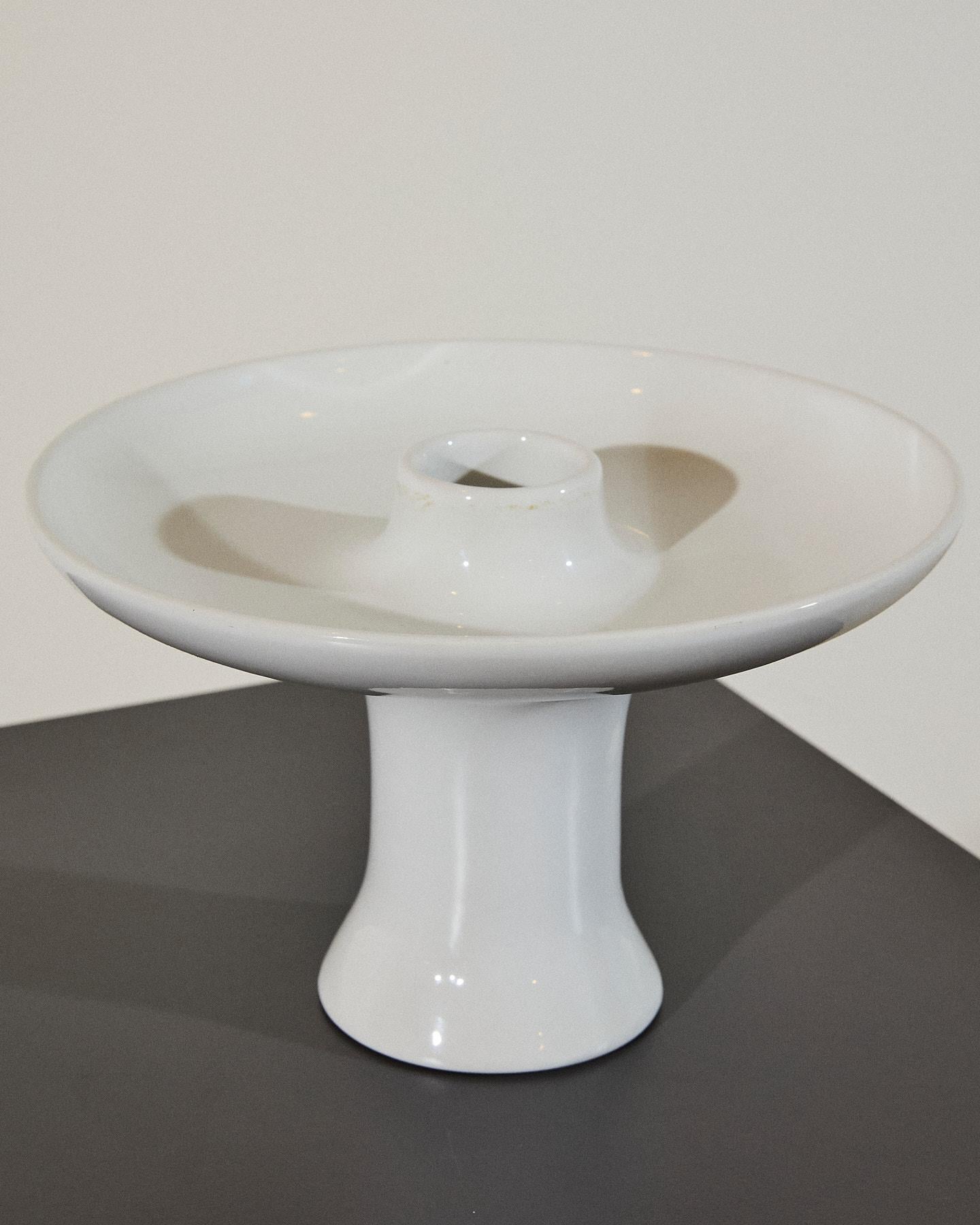 Raffinata alzatina in ceramica bianca lucida, disegnata da Angelo Mangiarotti per Fratelli Brambilla. 
L'oggetto, dalla forma scultorea ed essenziale, costituisce un esempio di design minimalista tipico del modernismo italiano e la sua eleganza lo