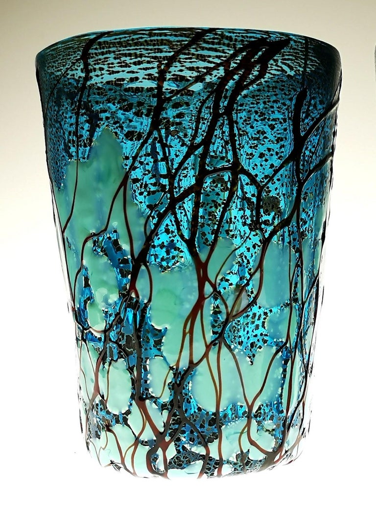 Two tumblers made in Murano in the 1990s by Amadi. Aquamarine glass is lined with silver leaf, afterwards the glass gets added spots in green opaline, finally vertical random relief drips of deep amethyst glass.

Elaborated and elegant finish,