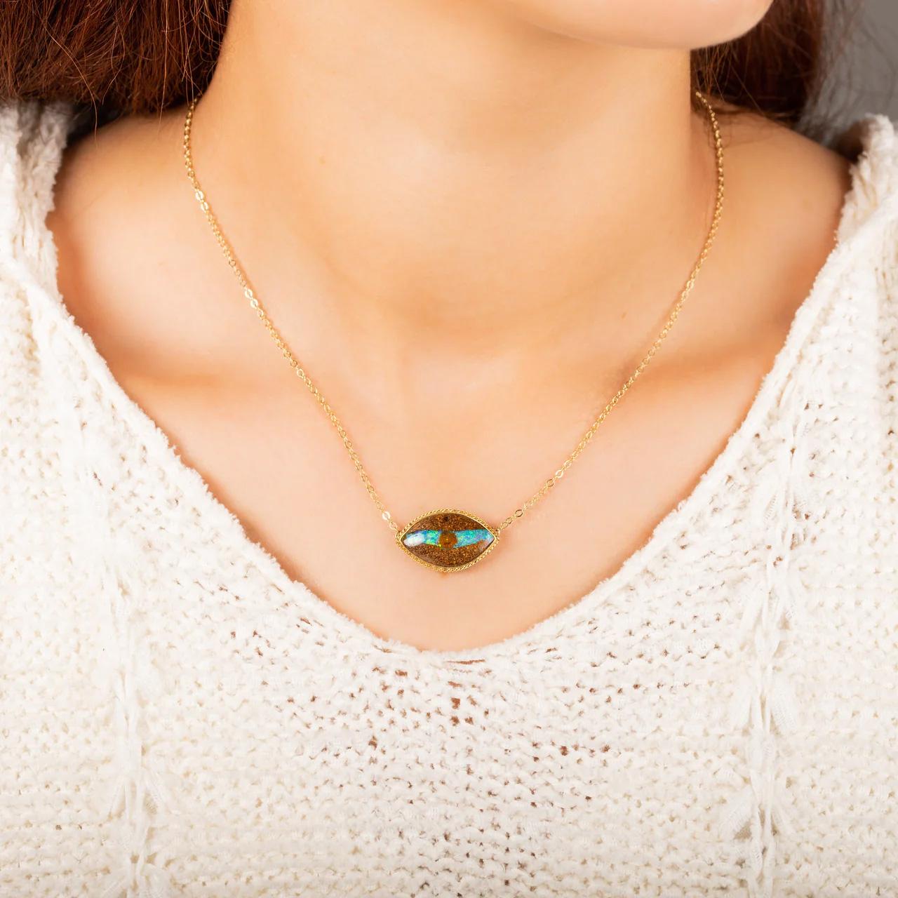 Qu'allez-vous espionner avec votre œil d'opale ? Les côtés sombres et texturés de ce bois opalisé s'écartent pour révéler une bande d'iridescence bleue et verte électrique bissectée par un cercle plus sombre, un effet naturel qui ressemble à une