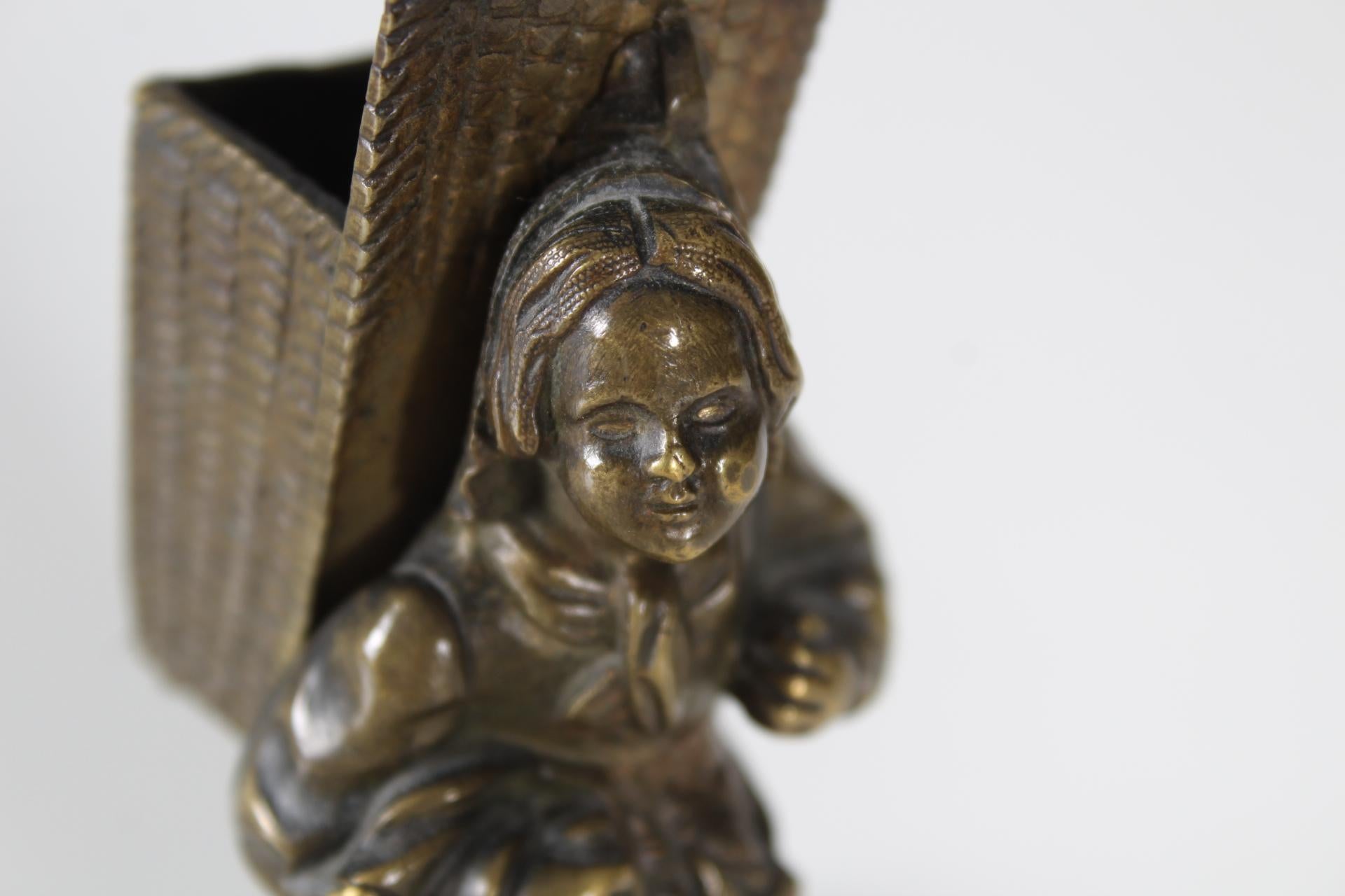 Beautiful, small bronze figure, probably a holder for matches.
The pannier on the back of the sculpture can be used to store small items. For example, paper clips on the work desk.
Nicely chiseled bronze work.

