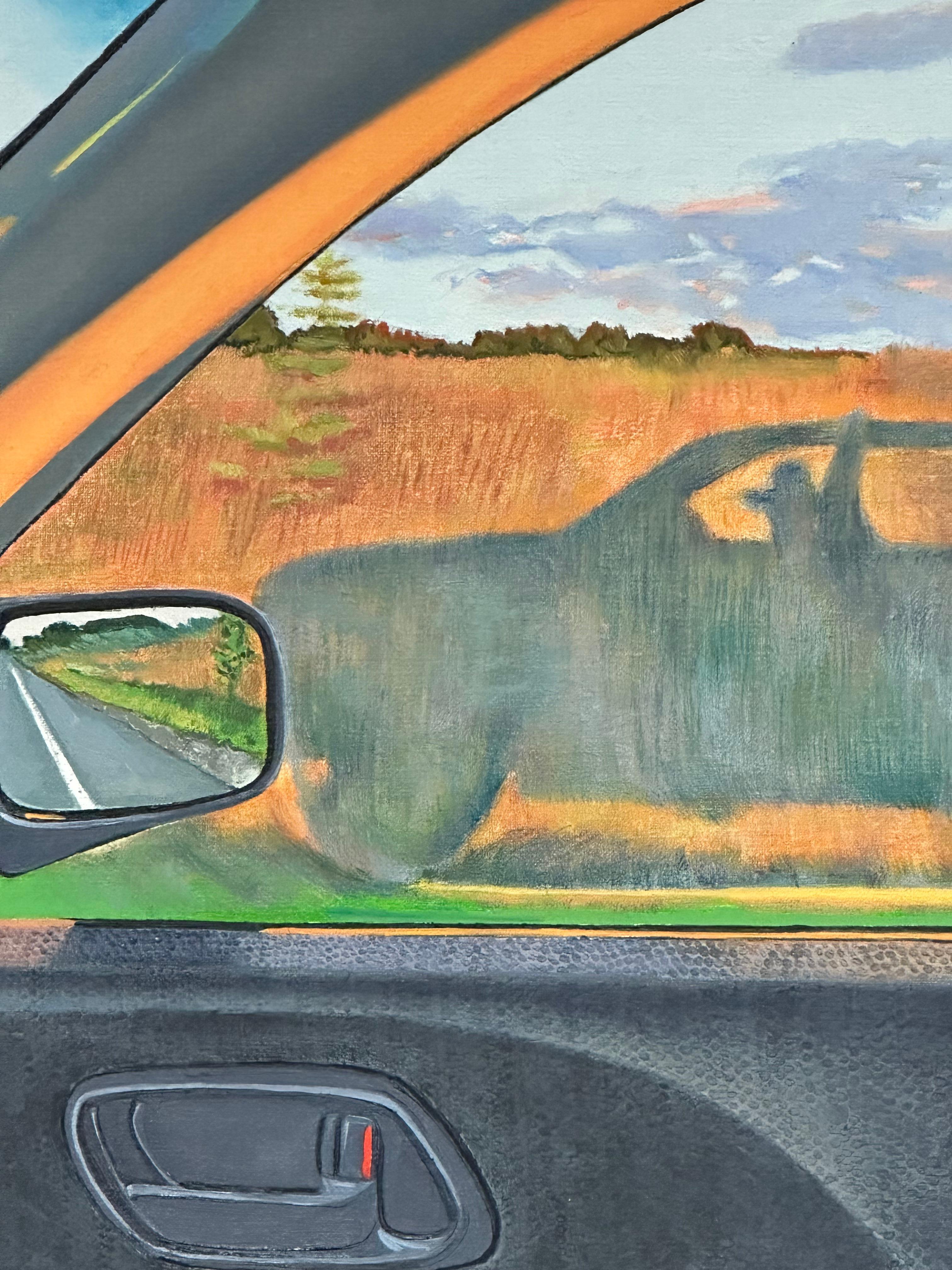 A peaceful landscape with a field, blue sky overhead and tree line on the distant horizon is seen through the window of a car in this contemporary oil panting on panel. Framed in a thin, light natural wood float frame. Signed and dated on