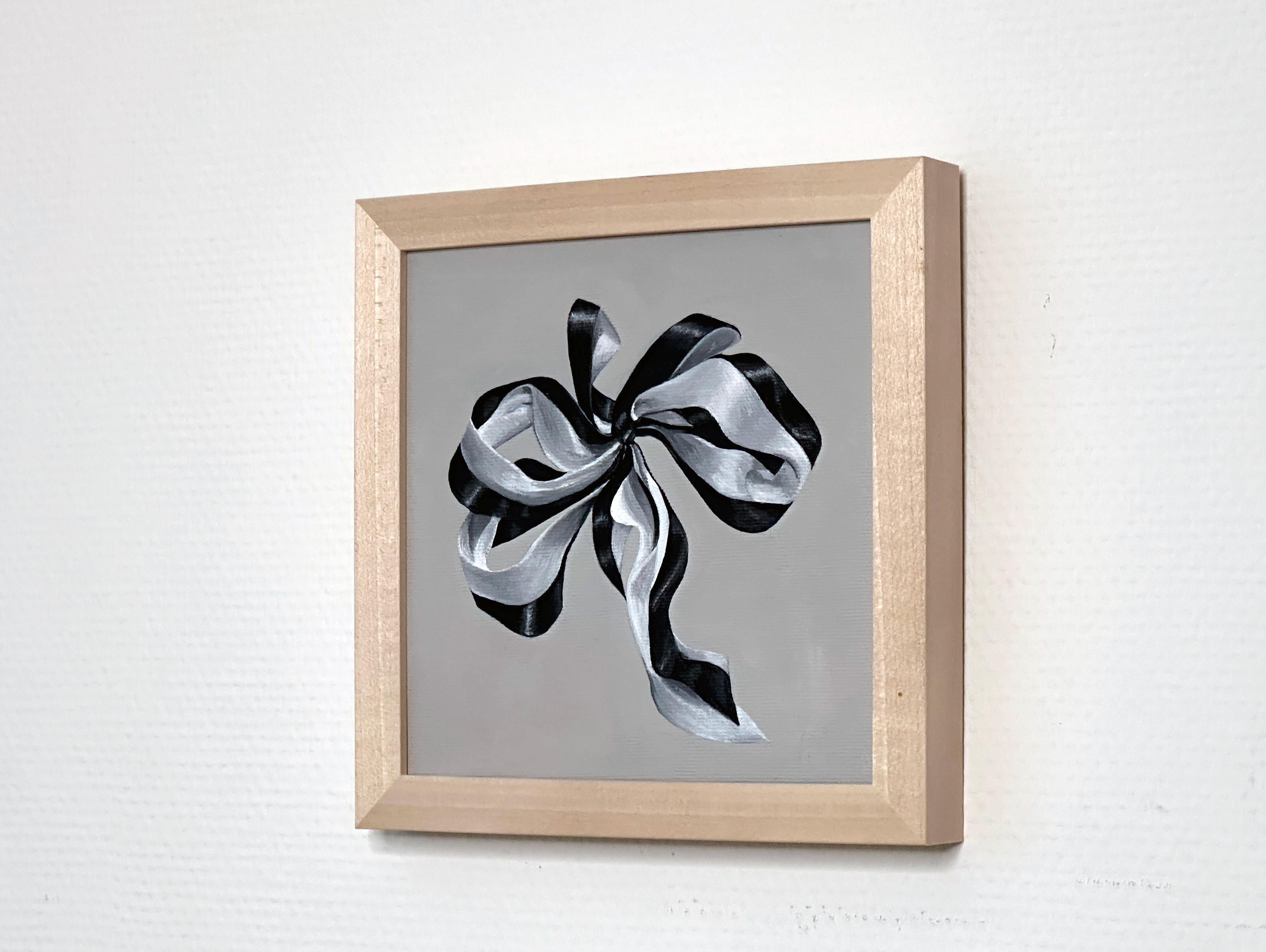 A small abstract painting made in 2023 by Amanda Andersen.
Minimal Christmas. / Minimal Valentine.
An elegant, intimate piece of art, depicting a delicate ribbon that is tied firmly in a structured, sharp, bow on a solid grey background. The