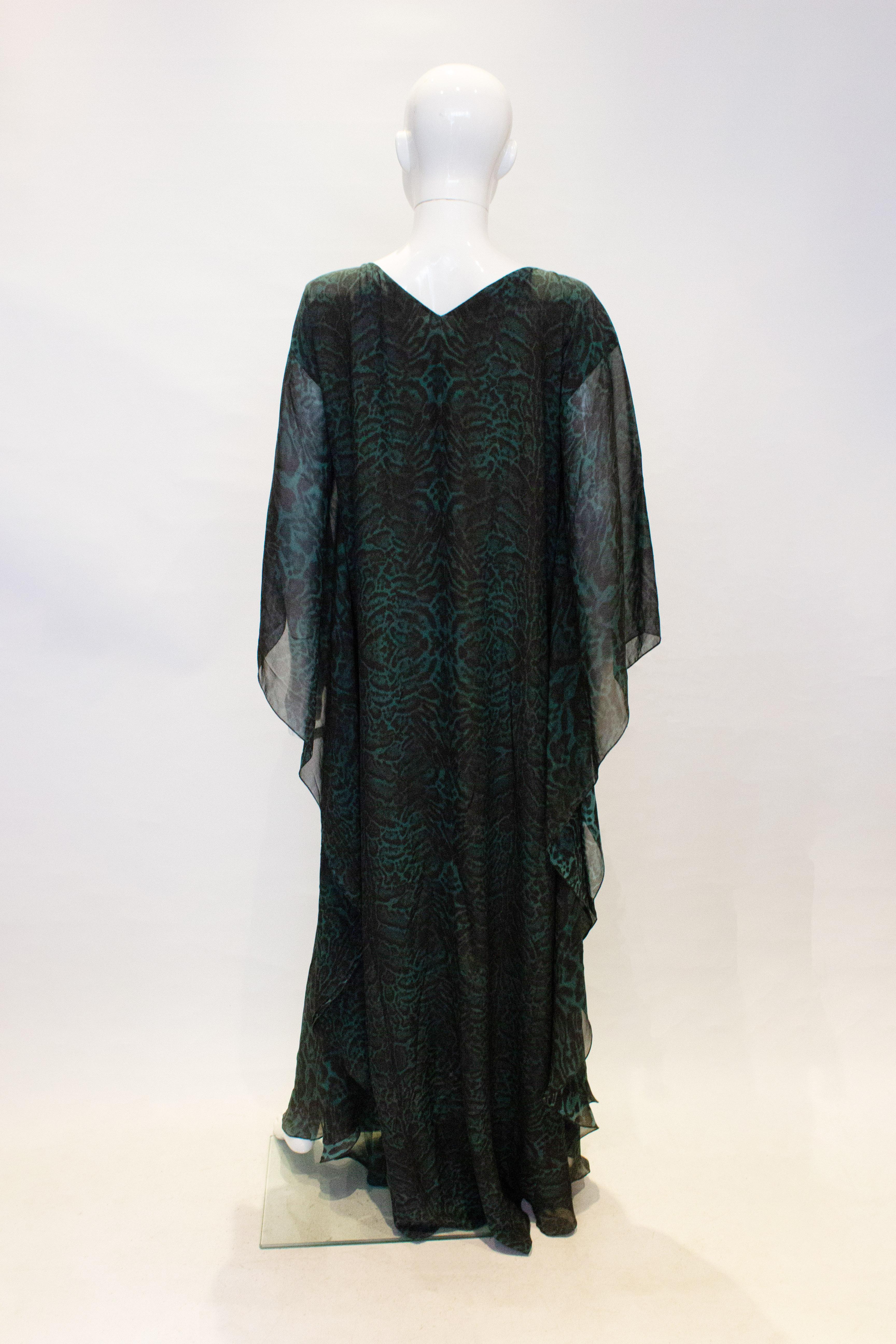 A wonderful kaftan for wafting by Amanda Wakely , London. The fabric is a beautiful sea green and black print with metal detail and a tie opening at the front, it as a v backline. Measurements :bust up to 40'', length 63''