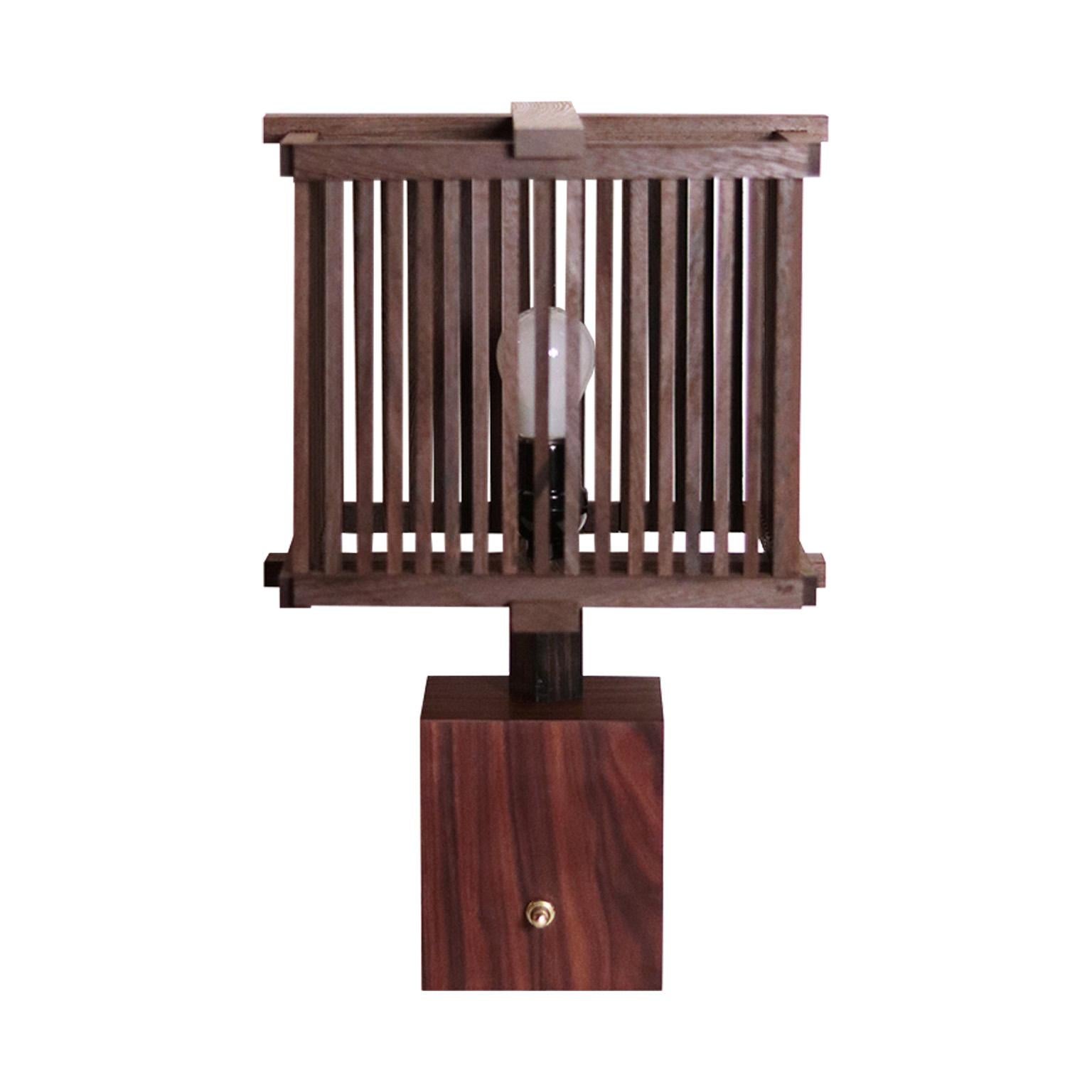 La lampe Amar est entièrement fabriquée à la main. L'abat-jour est en bois de wengé.  Un revêtement léger finement détaillé, avec une menuiserie visible, des lattes complexes, le tout au service de la mise en valeur de la beauté du wengé.  La base