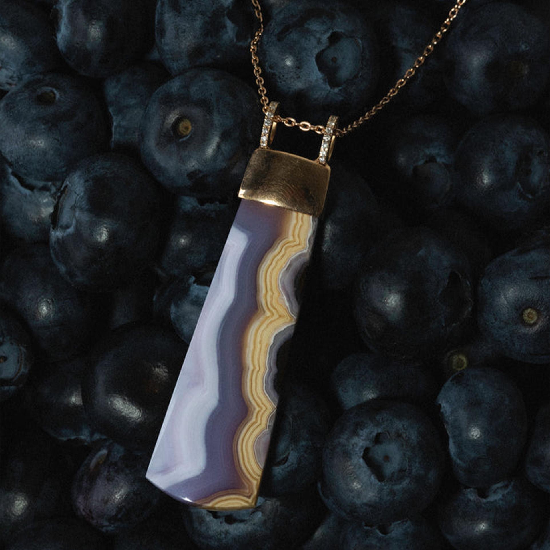 The AMARIS Pendant features an exquisite 5.5 cm agate drop, framed in luxurious 18k rose gold. This elegant piece combines the natural beauty of agate with a refined, modern design. The pendant is accented with two diamond hooks that add a touch of