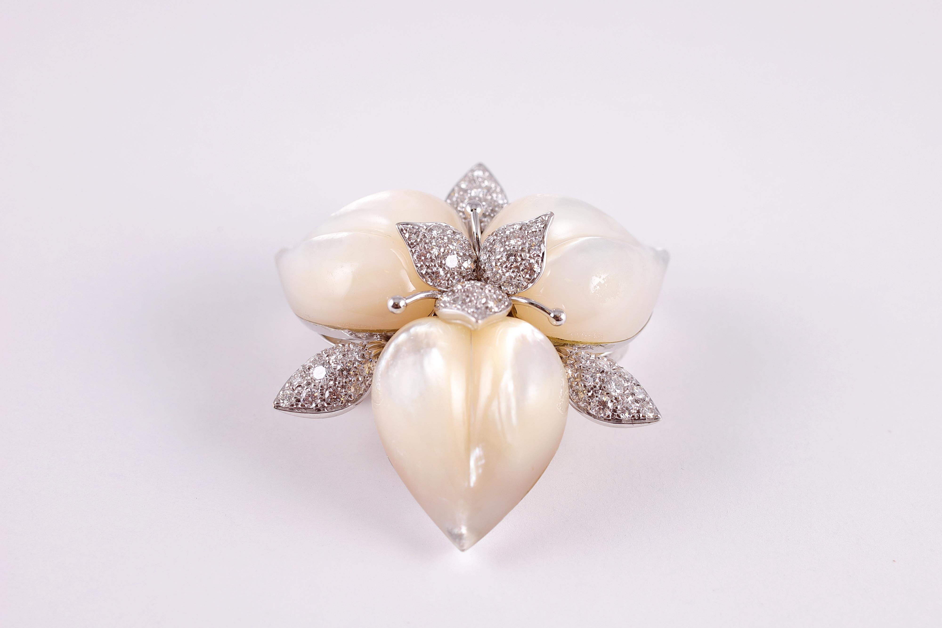 Three carved mother-of-pearl petals are enhanced by diamond leaves, and a diamond foliate cluster center, all in 18 karat white gold.  Total stated weight is approximately 1.91 carats. Secured with a double stem pin and plunger clasp. Purchased from