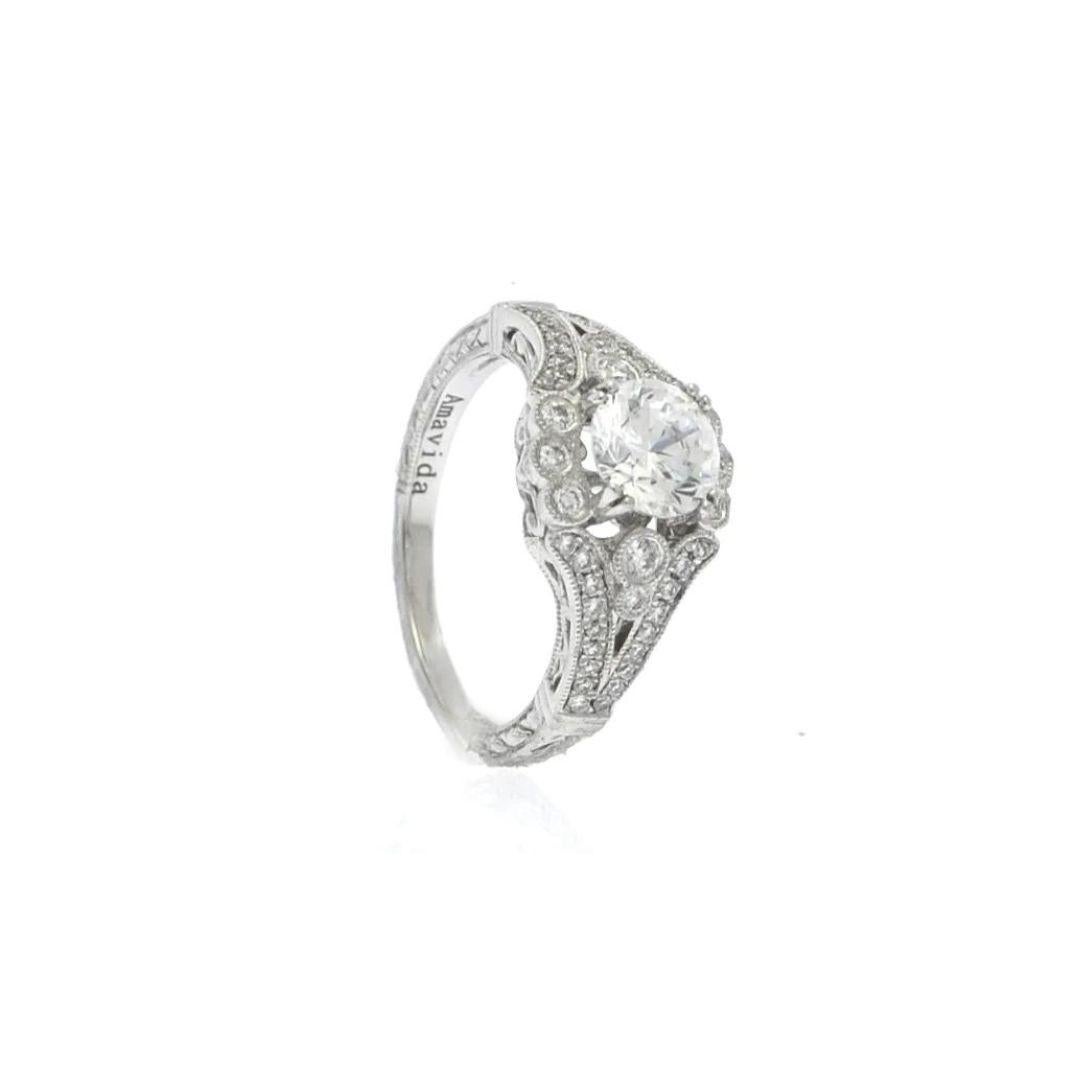 This platinum engagement ring is rich in design reminiscent of early 20th century English jewelry fashion. The antique inspired designs are everywhere, starting with the milgrain on the bezel set diamonds surrounding the center stone and finishing