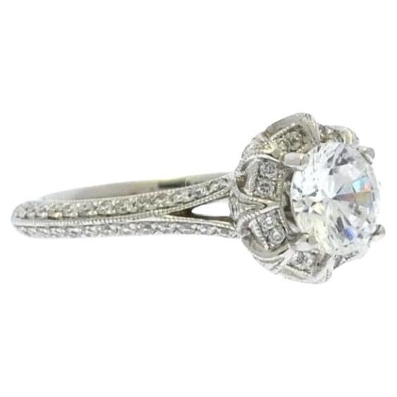 This intriguing platinum engagement ring reminisces the clean lines of a TIffany style setting solitaire, but it has subtle yet rich details. Antique flair designs combine with a Duchess style halo to create a vintage look with a contemporary touch.