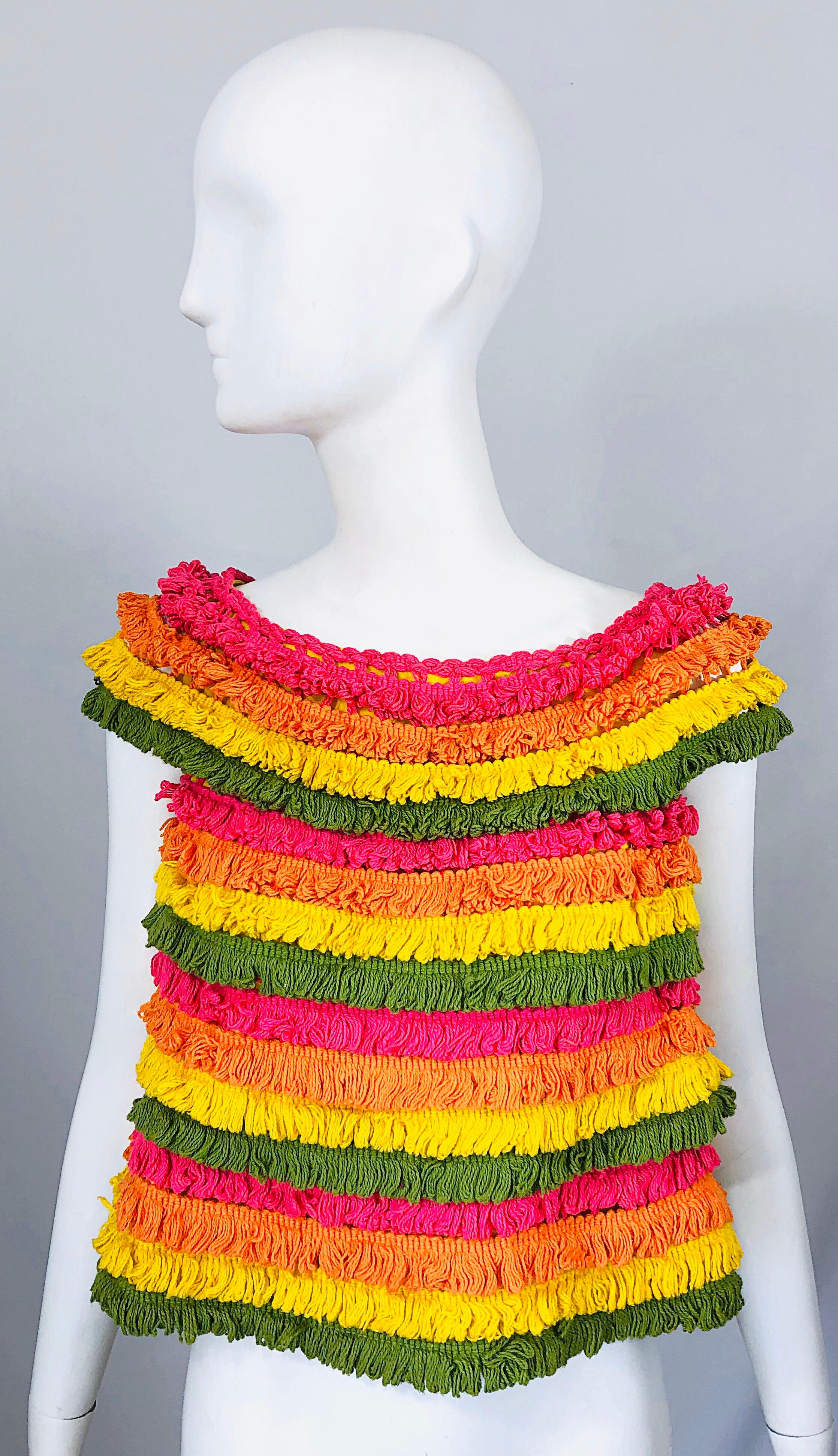 Amazing 1960s GENE OSTROW of Geno of California fringe trapeze crop top! Features vibrant colors of pink, orange, olive green and yellow throughout. Canary yellow base with tiers of cotton fringe. Simply slips over the head. Flattering flared hem.