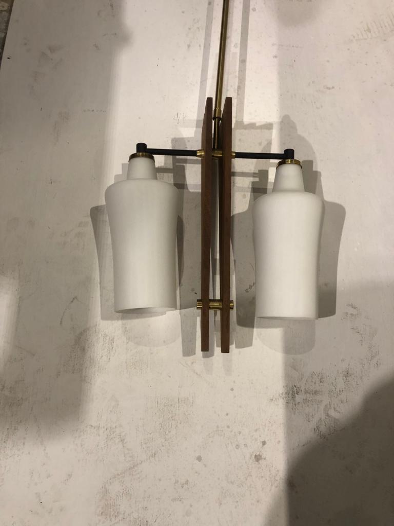 A rare Italian brass and glass chandelier made in the 1960s in the manner of Stilnovo. In brass it is in original patina, the original white opal glass glasses are in perfect condition, it works at 110-240 volts and requires two normal e14 bulbs.