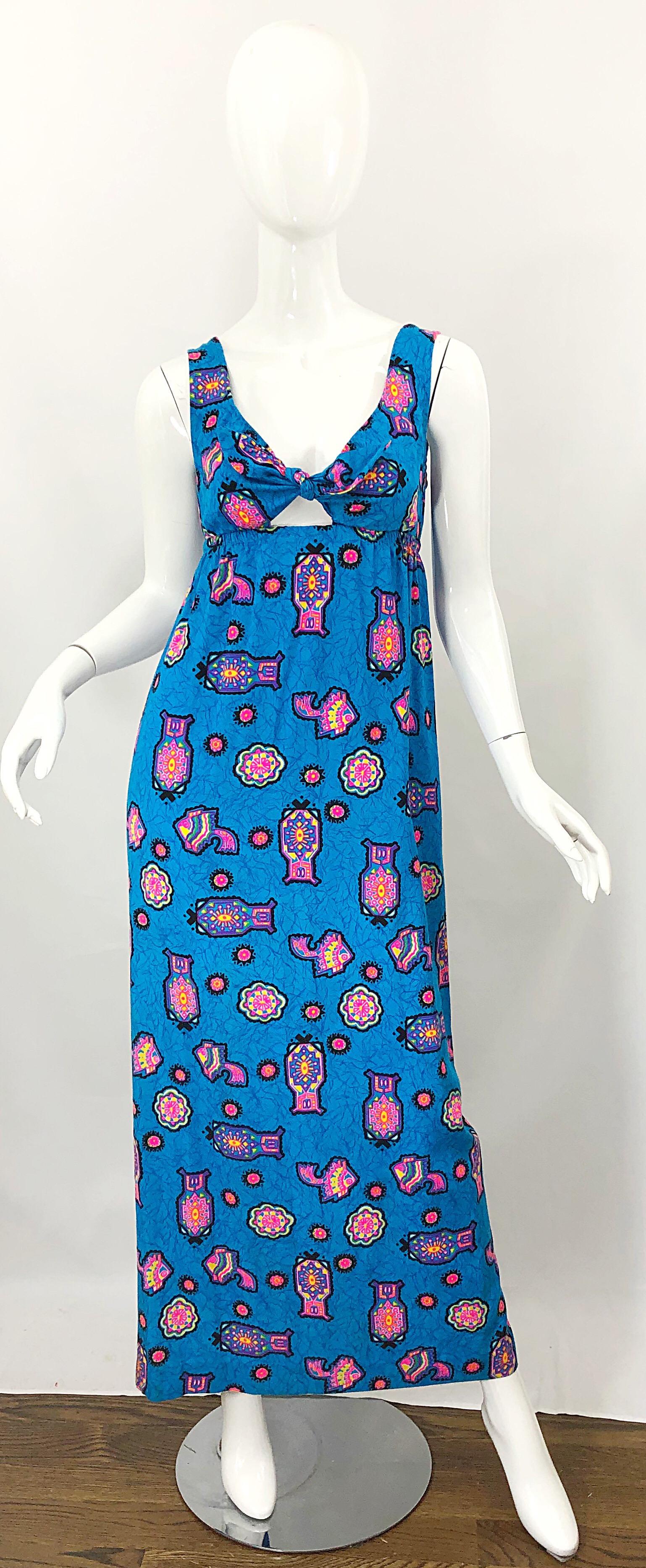 Amazing 1970s cerulean blue and pink cotton blend Aztec abstract print cut-out maxi dress! Features vibrant colors of hot pink, yellow, purple, and green throughout. Simply slips over the head, and stretches with an elastic high waist. Ties at the