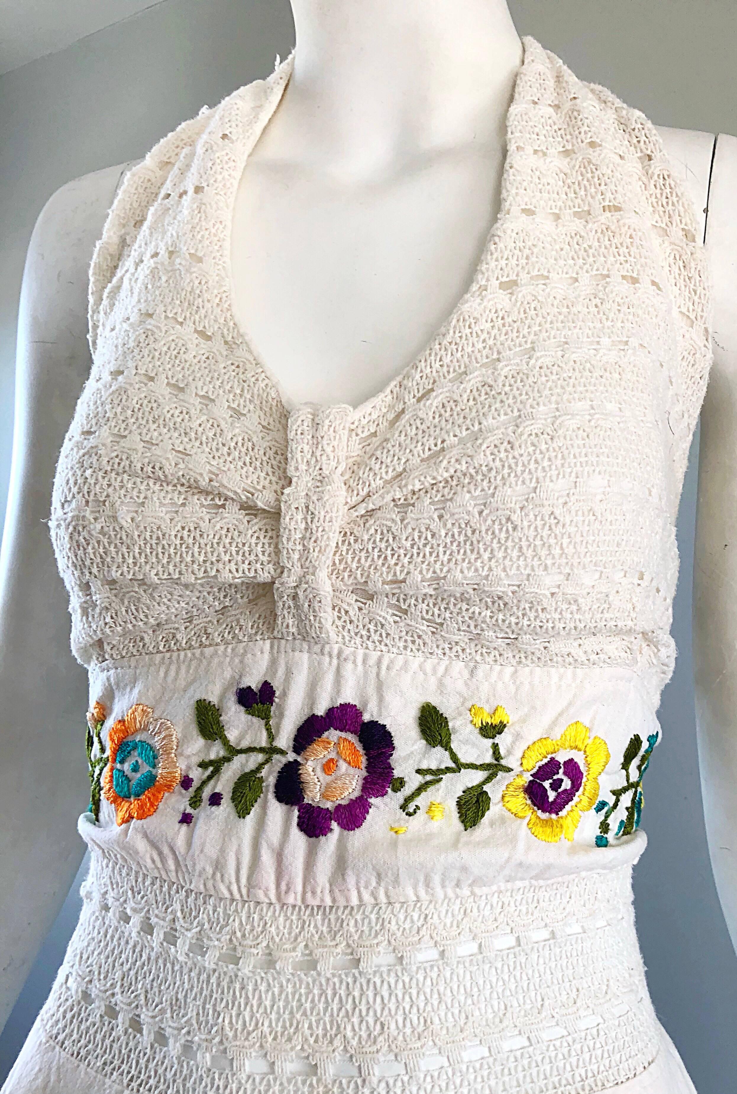Amazing 1970s ivory / off-white cotton embroidered hanky hem halter dress! Features a crochet bodice with flowers embroidered in purple, blue, yellow, orange, yellow and green. Asymmetrical flirty handkerchief hem looks amazing on! Ties at the top