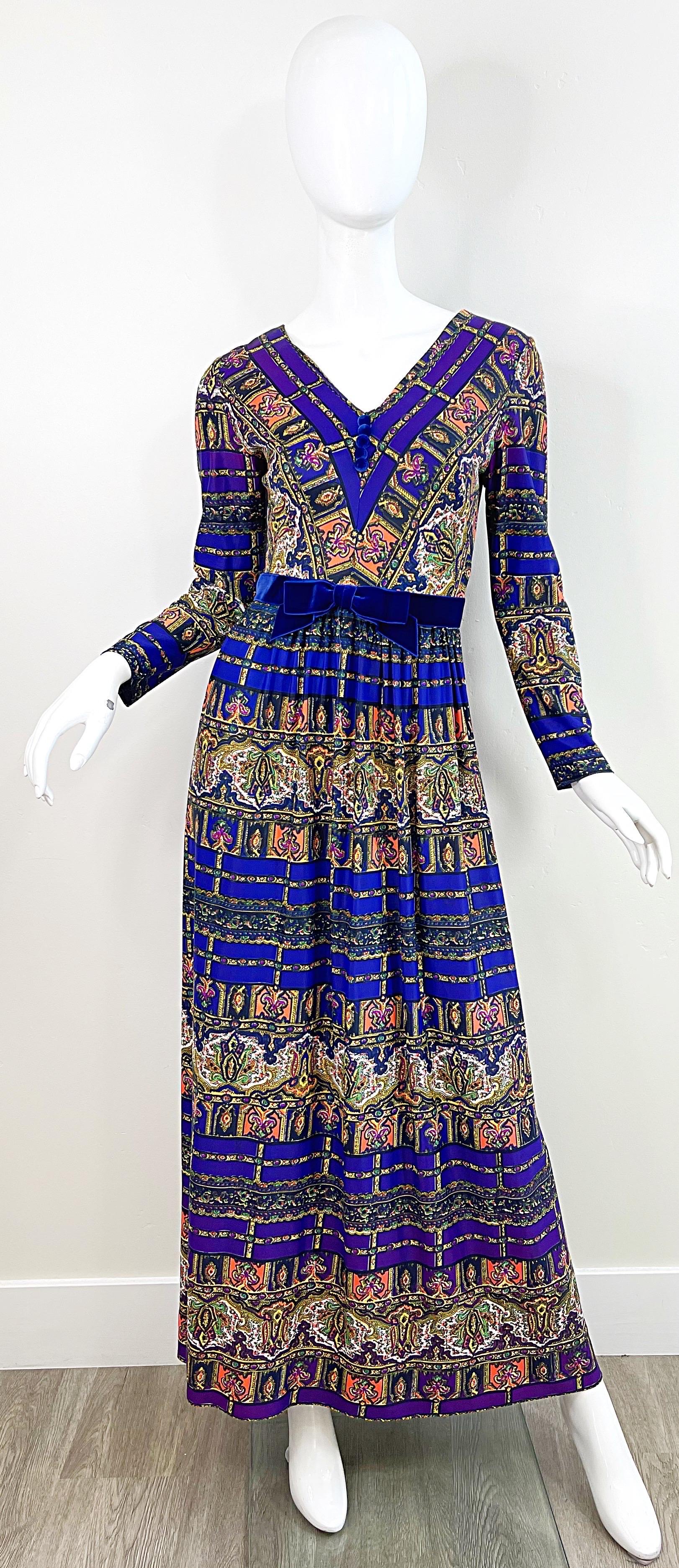 Amazing 1970s Moroccan print long sleeve purple maxi dress ! Features vibrant colors of orange, fuchsia, green yellow, pink and blue throughout. Royal velvet bow belt attached at waist. Hidden metal zipper up the back with hook-and-eye closure.