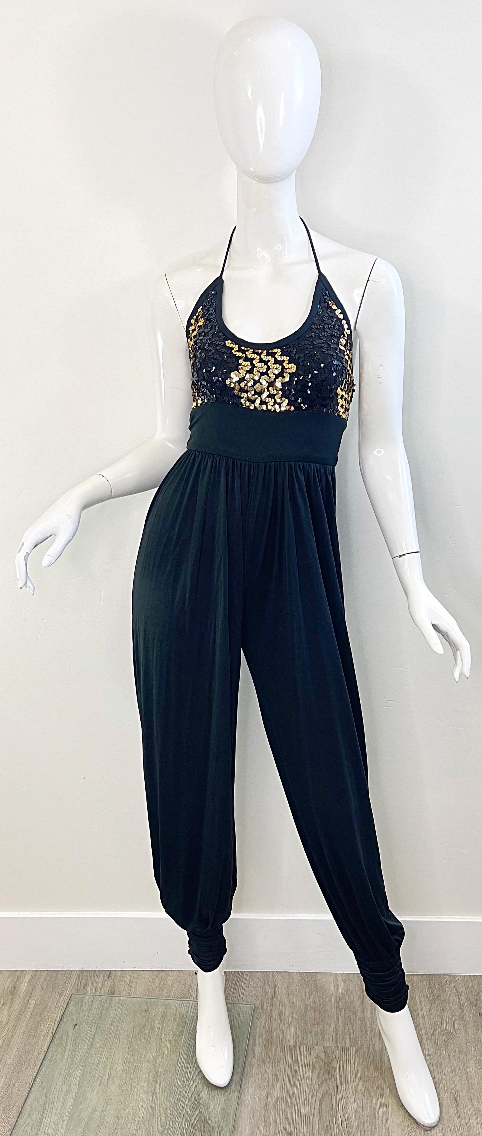 Amazing early 80s black and old jersey disco / Studio 54 harem pant halter jumpsuit ! Features hundreds of and-sewn gold and black sequins on the bodice. Halter neck ties at back neck, with hidden zipper up the back. Fabric covered buttons at each