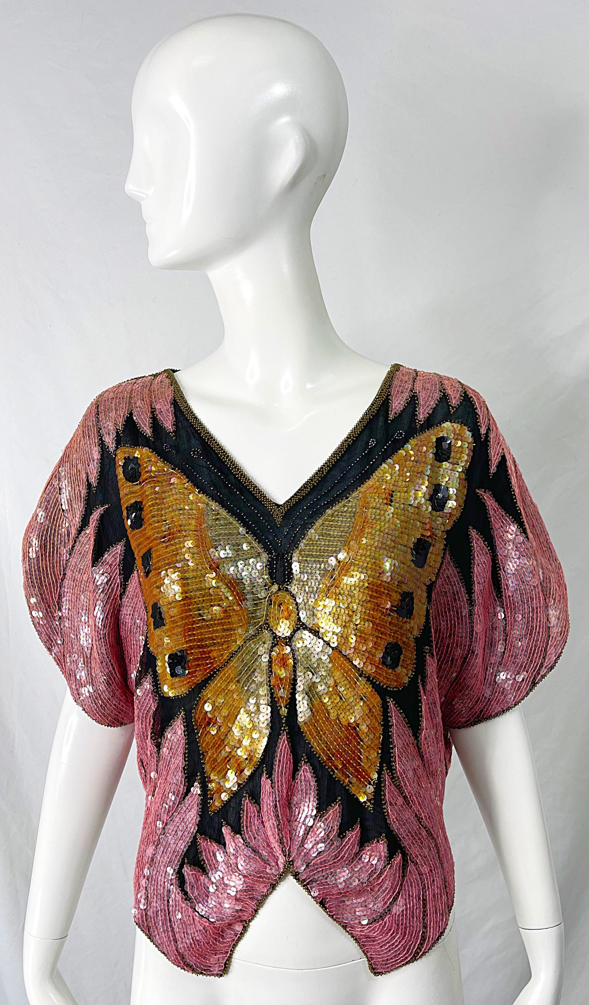 Amazing early 1980s butterfly silk fully sequined and beaded short dolman sleeve disco top ! Features a large butterfly in sequins on the front and back. Bright pink, gold and black colors throughout. 
In great condition
Approximately Size Medium /