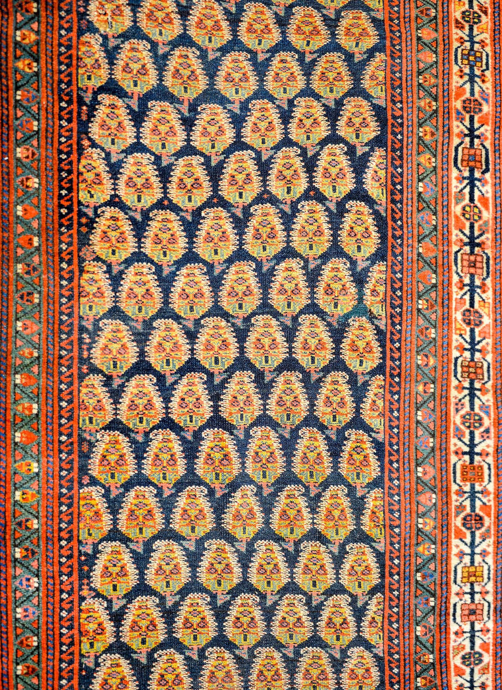 An amazing late 19th century Persian Afshar runner with a central field containing and all-over multi-colored paisley pattern woven in crimson, green, pink, gold, and indigo colored vegetable dyed wool, on a dark indigo background. The border is