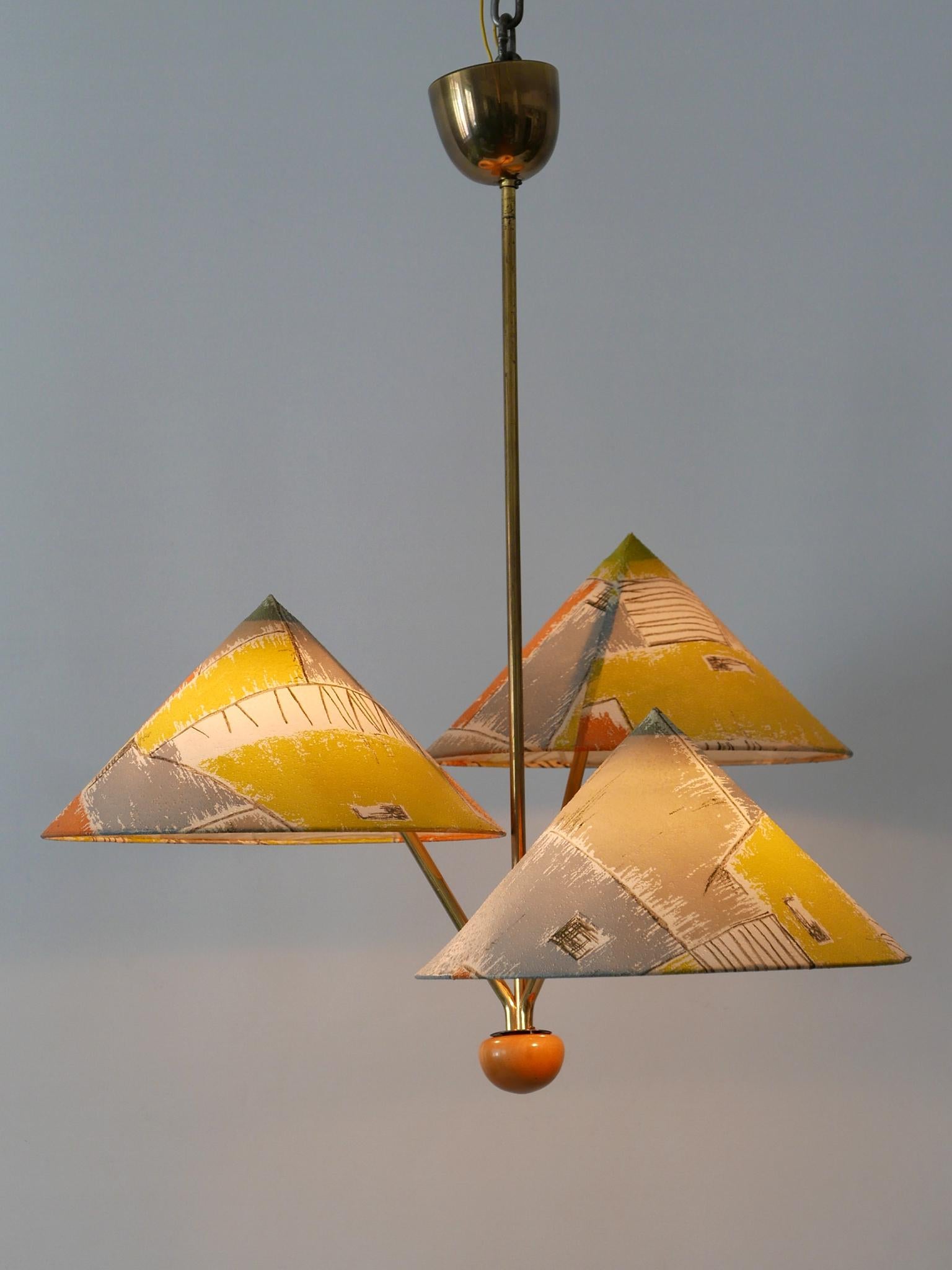Rare and highly decorative Mid-Century Modern three-armed pendant lamp or chandelier with lamp shades 'Chinese Hut'. Designed and manufactured by Rupert Nikoll, Austria, 1950s.

Executed in brass and multi-colored plastic lamp shades, the pendant
