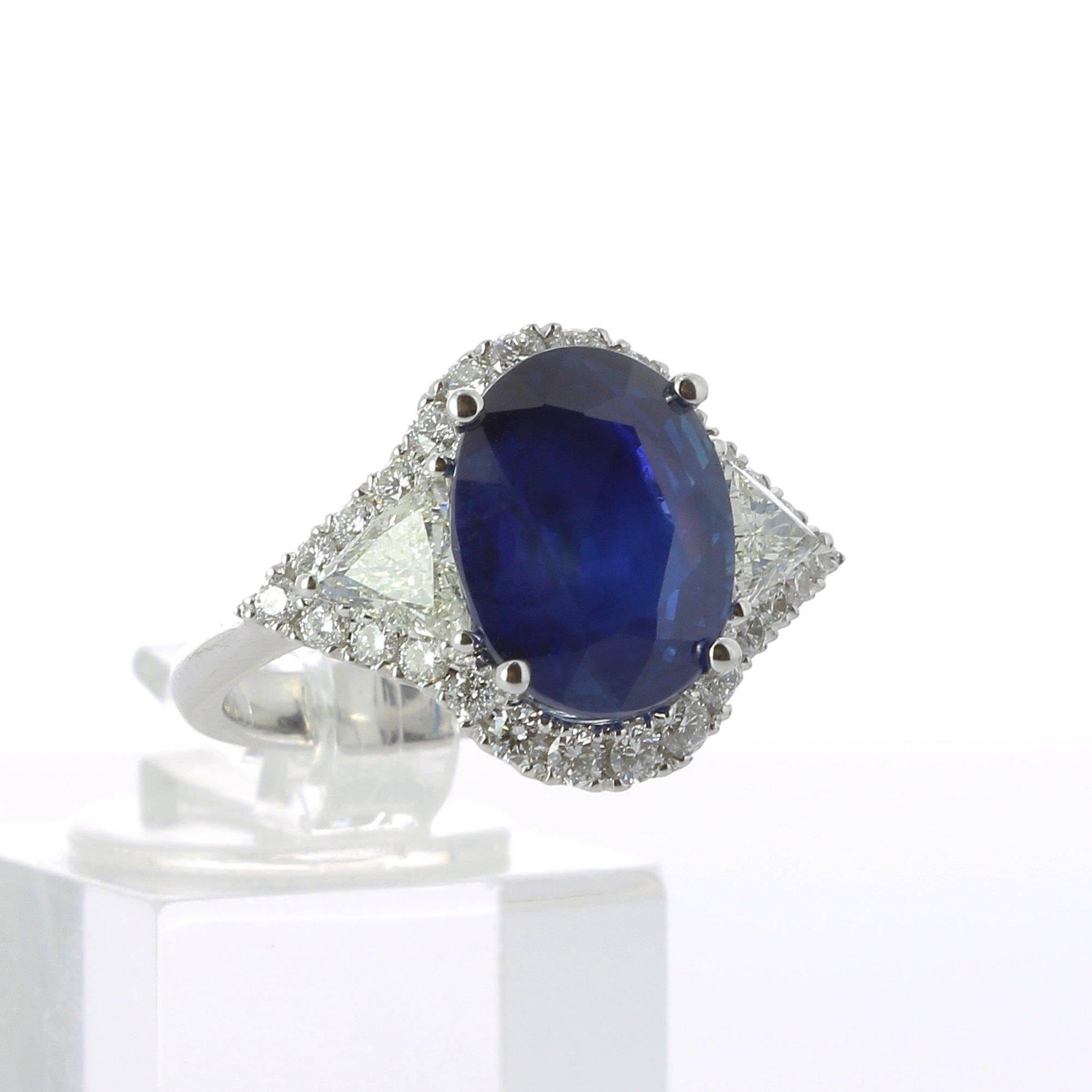 An amazing Oval Sapphire Ring, flanked on each side by a single Triangle Diamond and surround with an halo of Diamond weighing 0.26 Carats.
The total weight of the Sapphire is 5.29 Carats.
The halo of diamond is set with 26 Round diamond. 
The