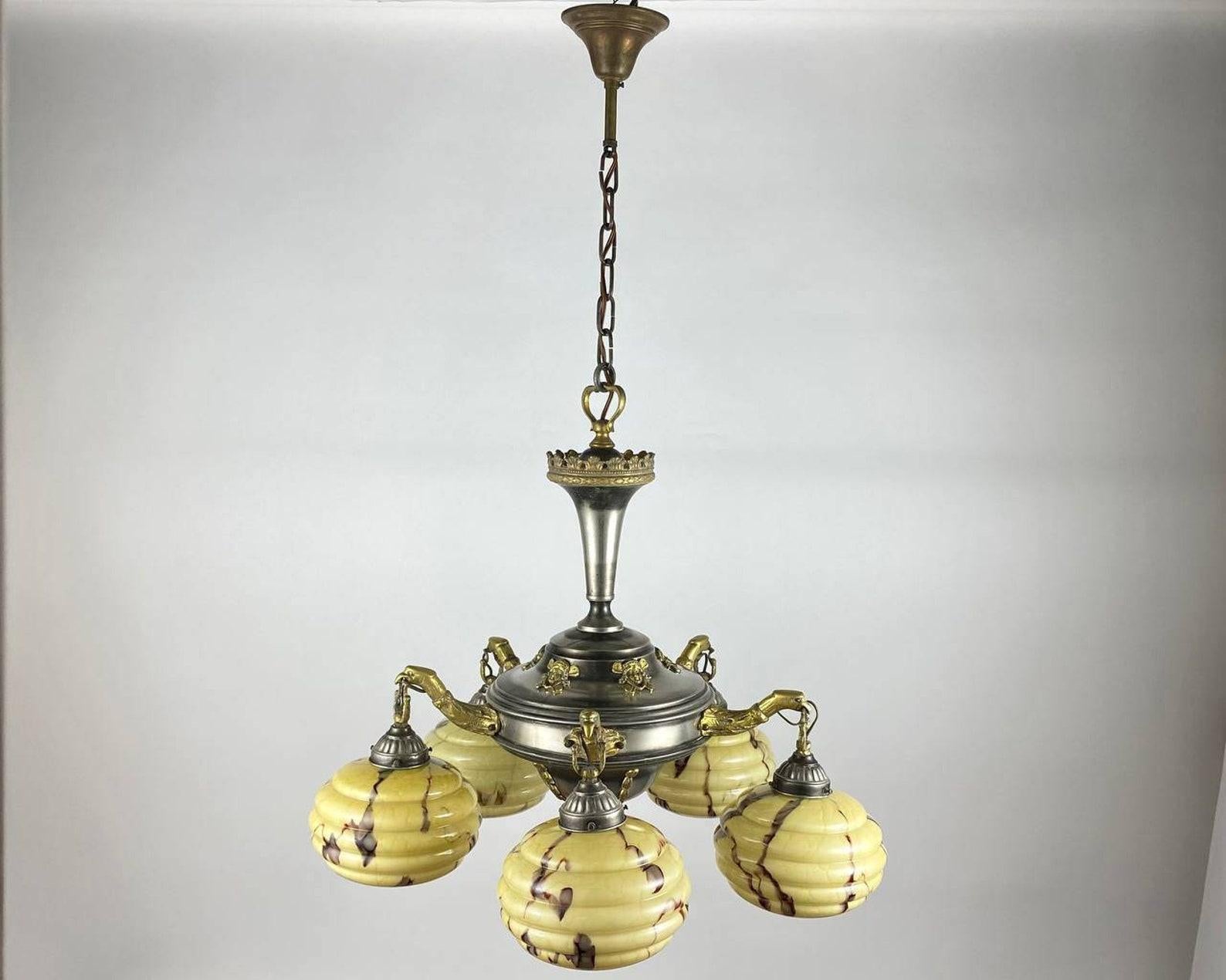 Antique brass chandelier with five glass shades. 

 France, 1930's. 

 Antique chandelier with five birds carrying bizarre plafond berries in their beaks. 

 The lampshades are made of colored glass of the color of melted milk, the metal parts