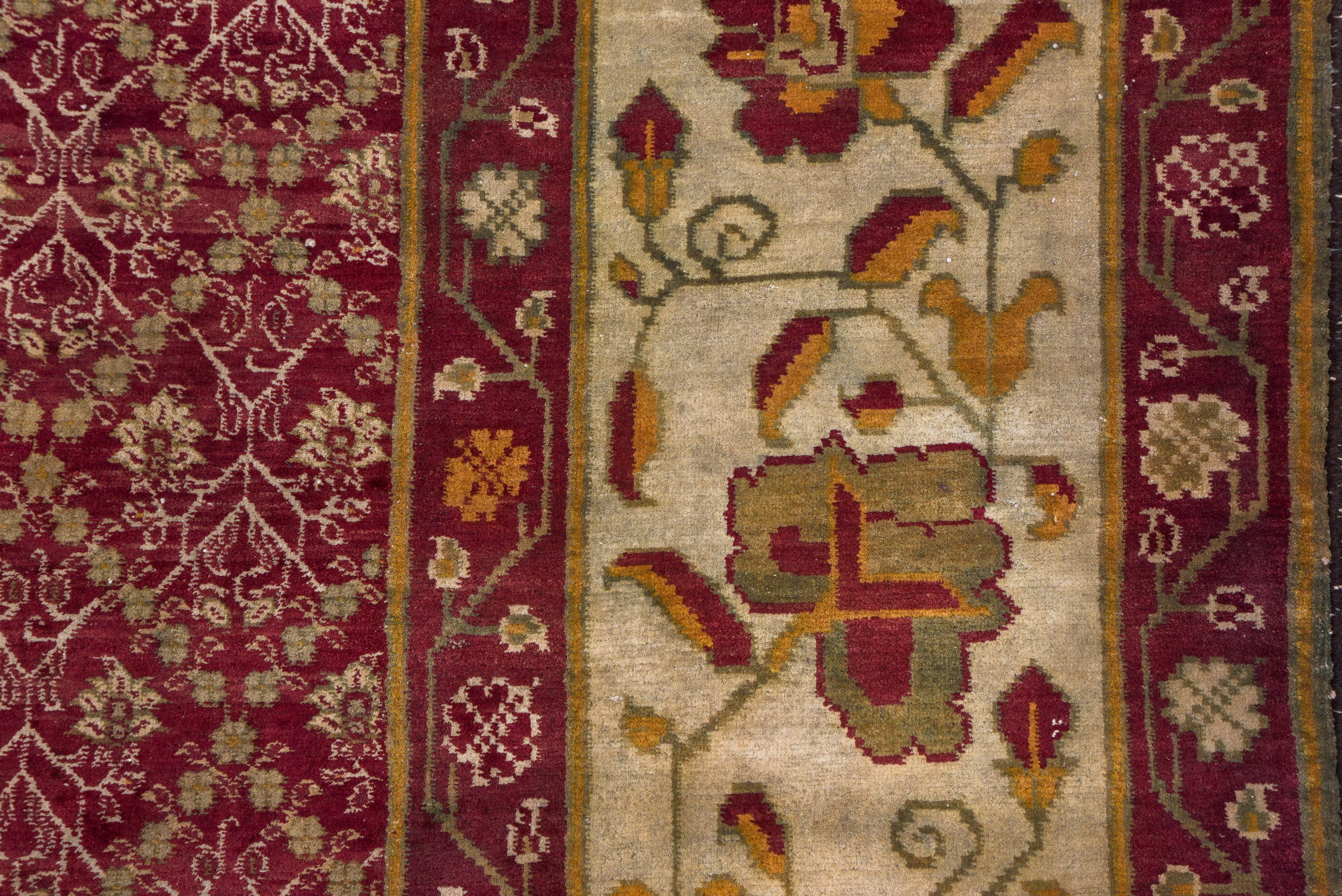 This palatial north Indian city carpet shows a repeating floral pattern constrained by a lozenge lattice, set within a wide sand border with tilted palmettes on an angular leafy vine.