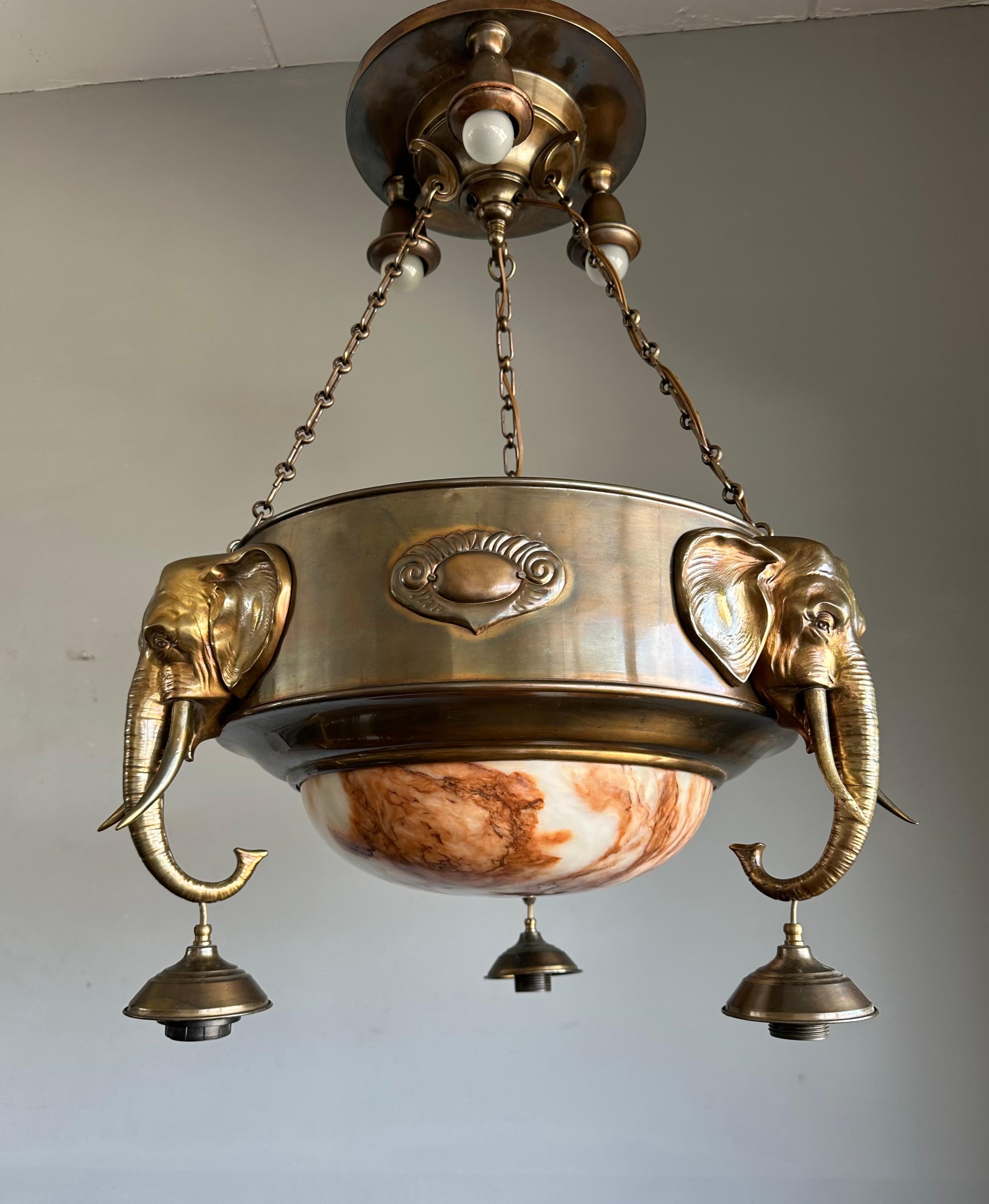 Große und bemerkenswerte Elefanten-Skulpturen aus Alabaster und Messing als Pendelleuchte.

Dieser seltene und bemerkenswerte 8-flammige Kronleuchter stammt aus der Zeit des europäischen Art déco (ca. 1920-1930) und ist aus gutem Grund sehr