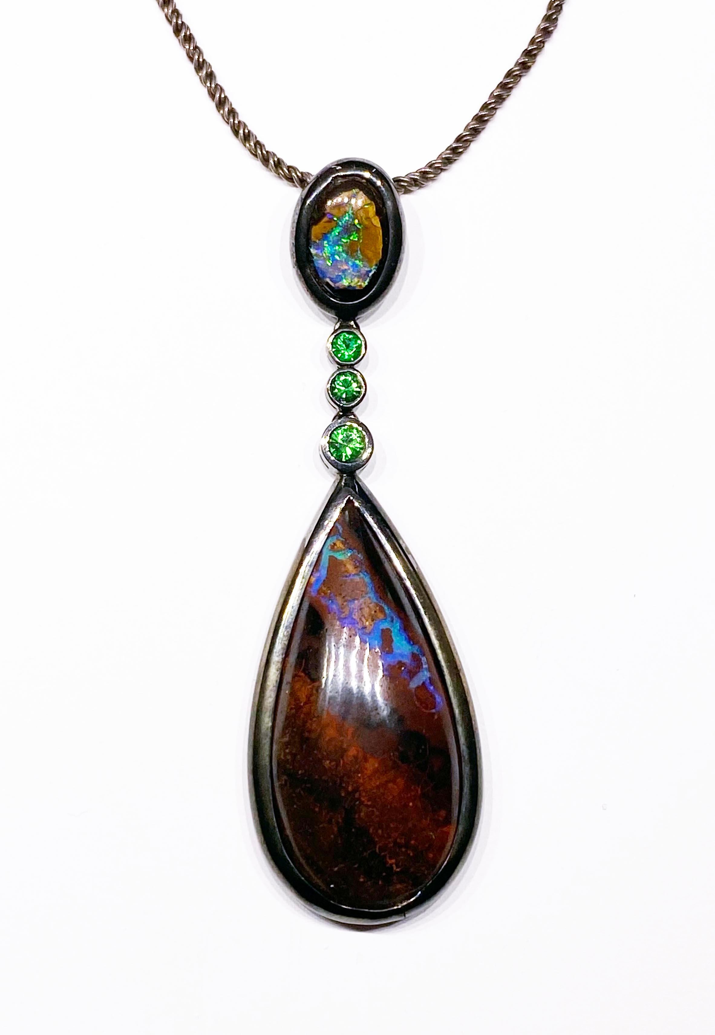 A  Boulder Opal & Tsavorite Garnet Pendant set in blackened Silver.
This Pendant features 2 Amazing Australian Boulder Opal Cabochons. The main Pear Shaped Cab is approxamately 40 Carats while the Smaller Oval is 5.22 Carats. Between are 3 Vivid