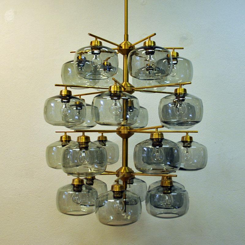 This large and exceptional chandelier consists of a polished brass frame and clear smoke colored glassdomes that all has a kind of pressed oval and special look.
The chandelier is designed by the Holger Johansson, Sweden (1911-1992) and produced by