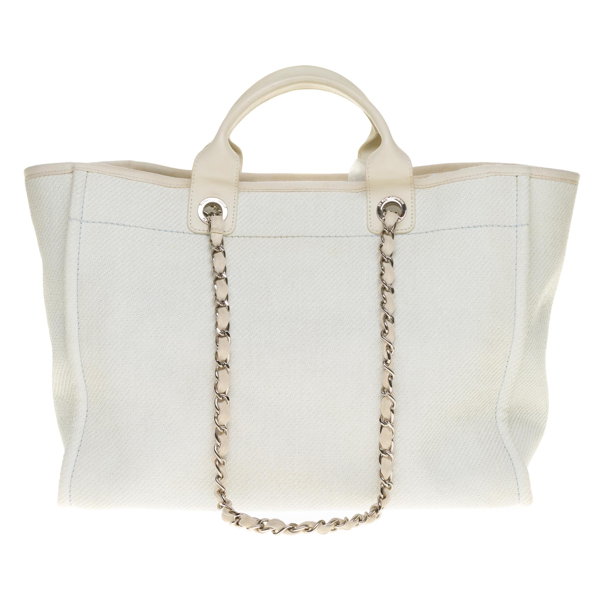 Beautiful Chanel Deauville white canvas tote bag, silver metal hardware, double white leather handle, double silver metal handle intertwined with white leather allowing a hand or shoulder support.

Blue canvas interior, two zipped