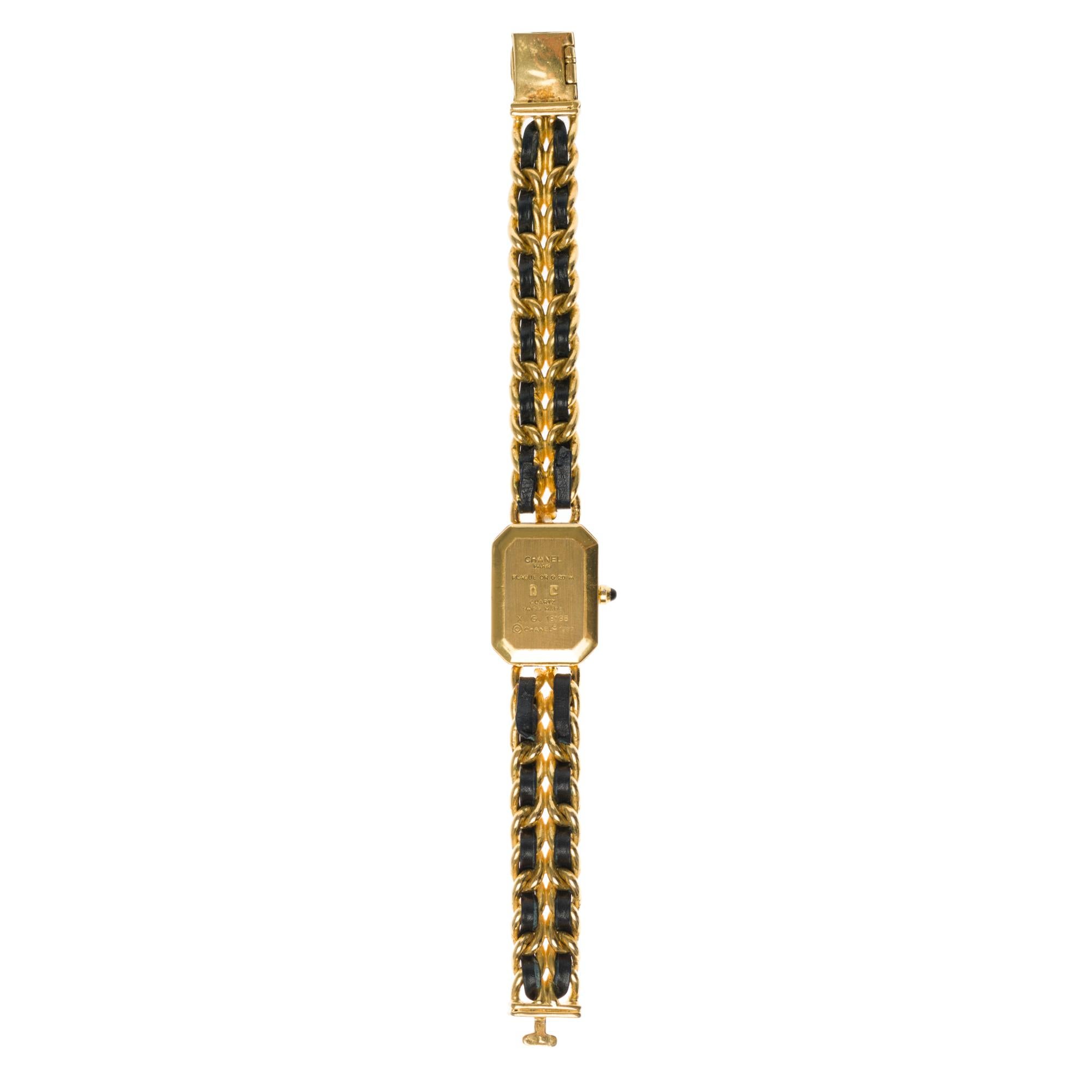 Chanel Première women’s wristwatch in gold plated. Octagonal case in gold plated with faceted glass, crown set with a black cabochon.

Black dial, quartz movement.
Gold plated stick needles.
Bracelet in gold and black plated and leather, clasp in