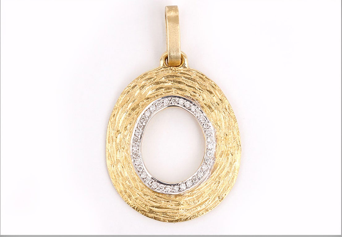 This beautiful pendant features a hammered look with 0.20 ctw. of diamonds on an 18k yellow gold chain. Pendant measures apx. 1-1/2 inches in length and 7/8-inch in width. Chain measures apx. 19-1/2 inches in length. Total weight is 7.5 grams.