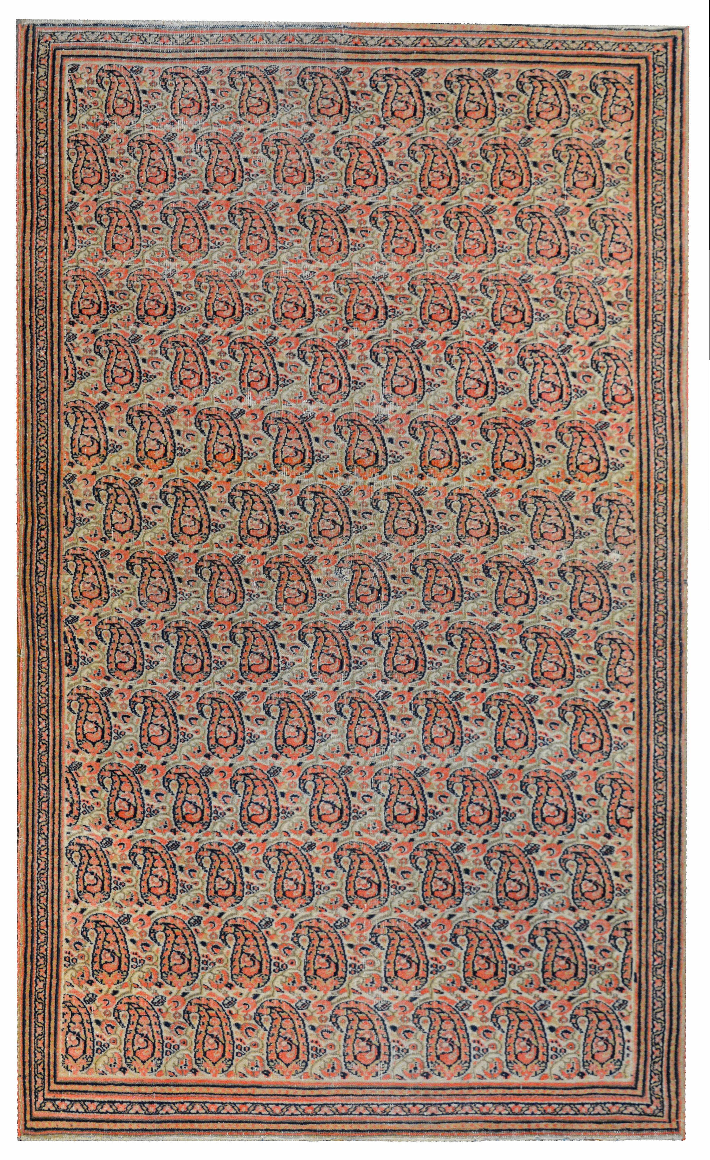 An amazing early 20th century Persian Doroksh rug with a mesmerizing all-over paisley pattern woven in pale orange, green, indigo, and cream colored vegetable dyed wool surrounded by a thin border composed of multiple thin petite patterned stripes.