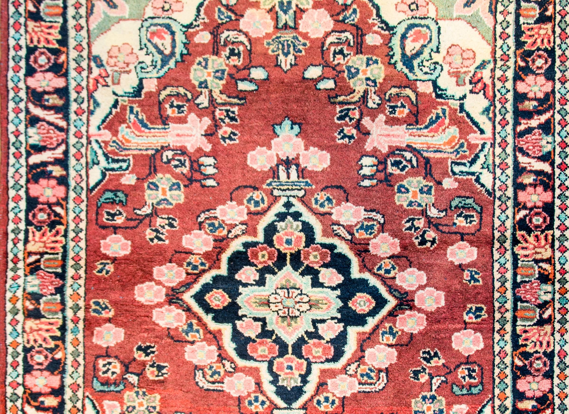 An amazing early 20th century Persian Mahal rug with wonderfully woven floral patterned diamond medallion on a dark cranberry colored background surrounded by an elaborate contrasting floral border. The border is wide with a central floral stripe