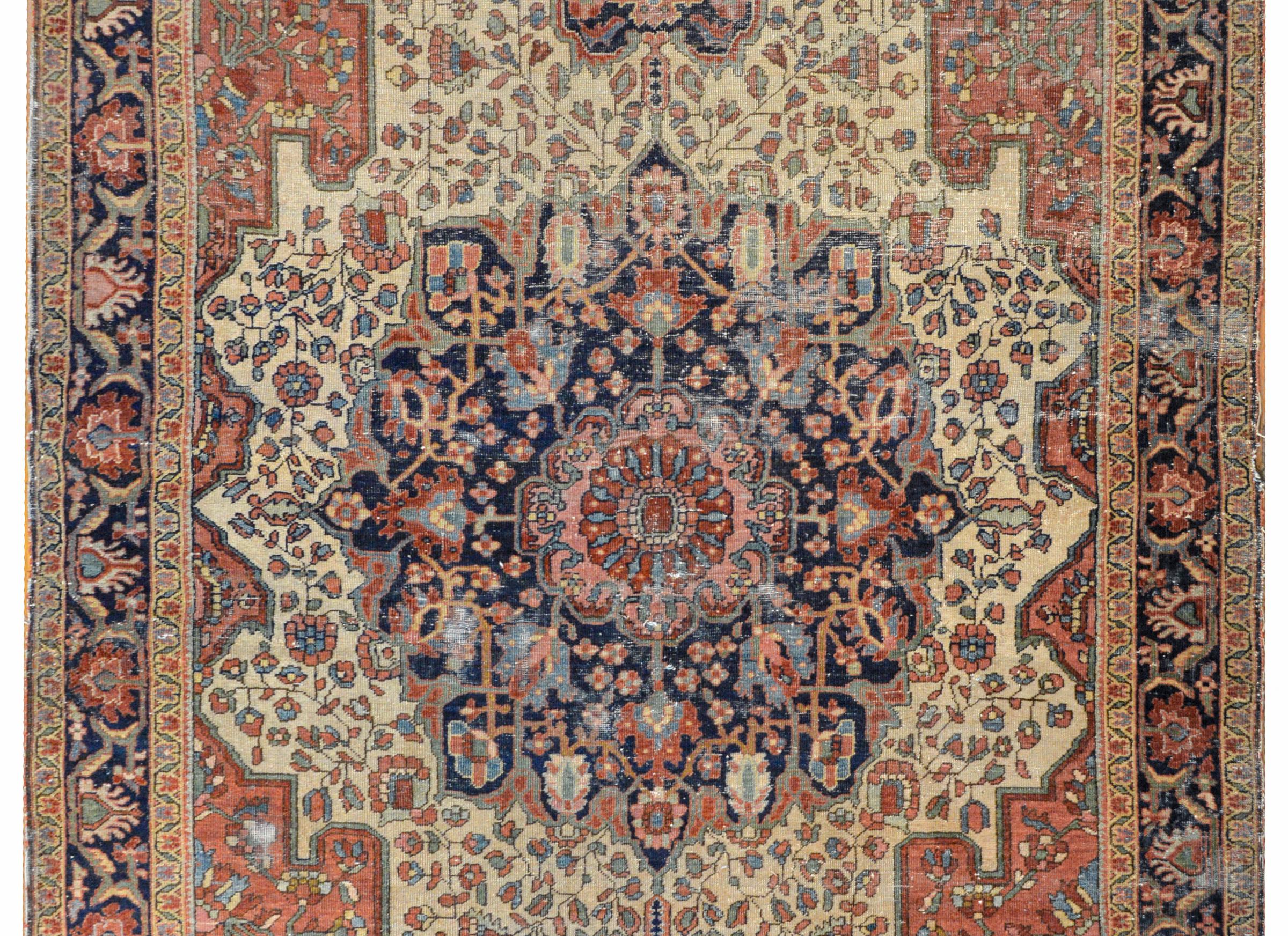An amazing early 20th century Persian Sarouk Farahan rug with a large central medallion composed of multiple flowers woven in crimson, light and dark indigo, brown and cream colored wool on a dark indigo background, all amidst another field of