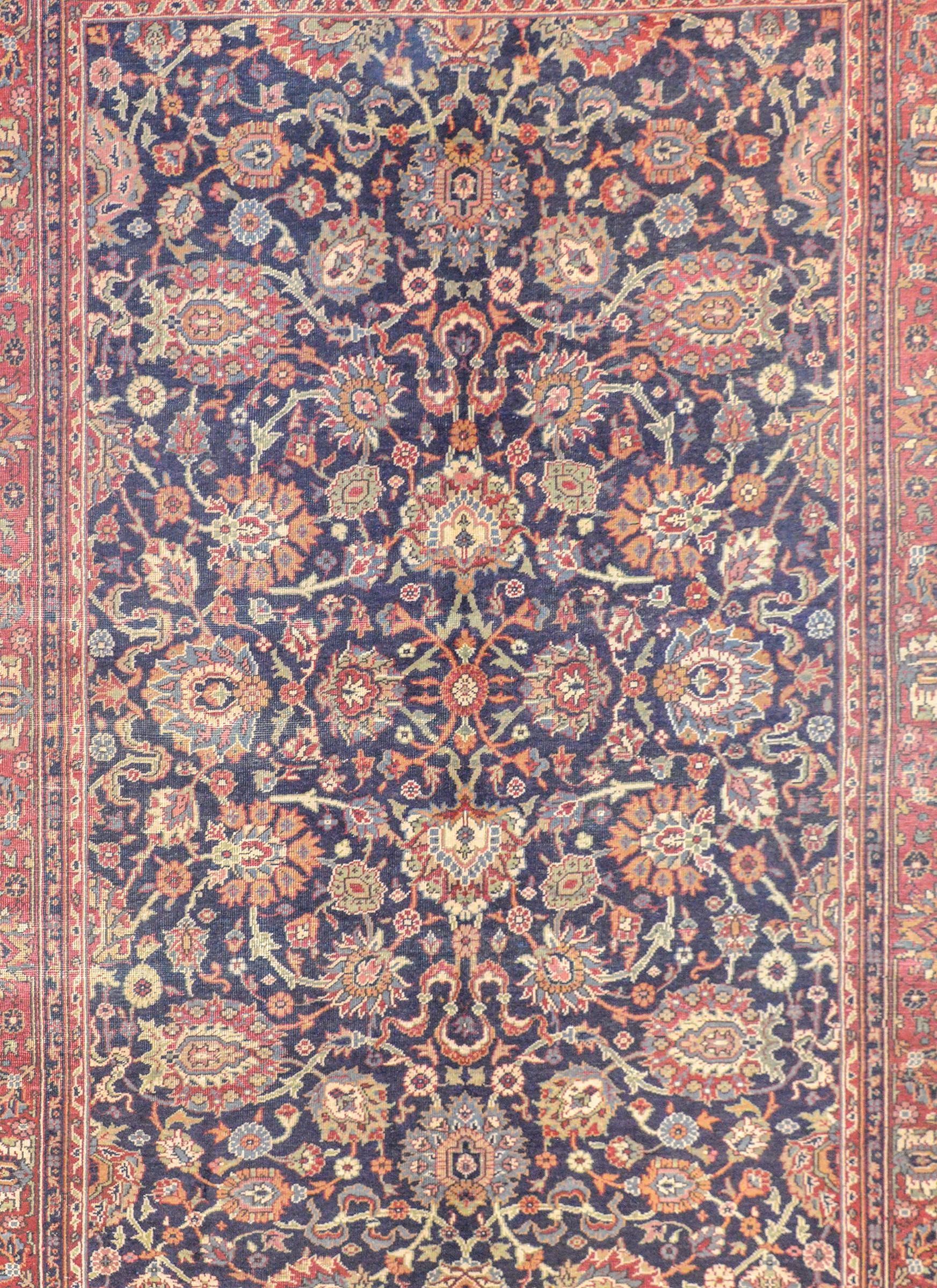 An amazing early 20th century Turkish Sparta rug with a fantastic all-over large-scale floral pattern woven in crimson, green, gold, and cream colored wool against a dark indigo background. The border is wide with a large-scale floral and vine