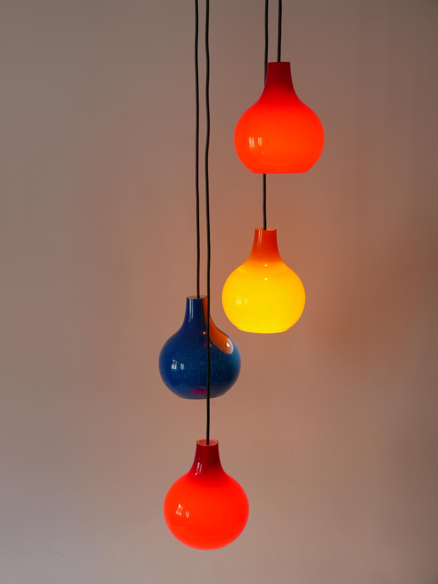 A breath taking light object. Extremely rare, lovely and highly decorative Mid-Century Modern four-flamed cascading pendant lamp or chandelier. Designed and manufactured by Peill & Putzler, Germany, 1970s.

Executed in red, blue and orange colored