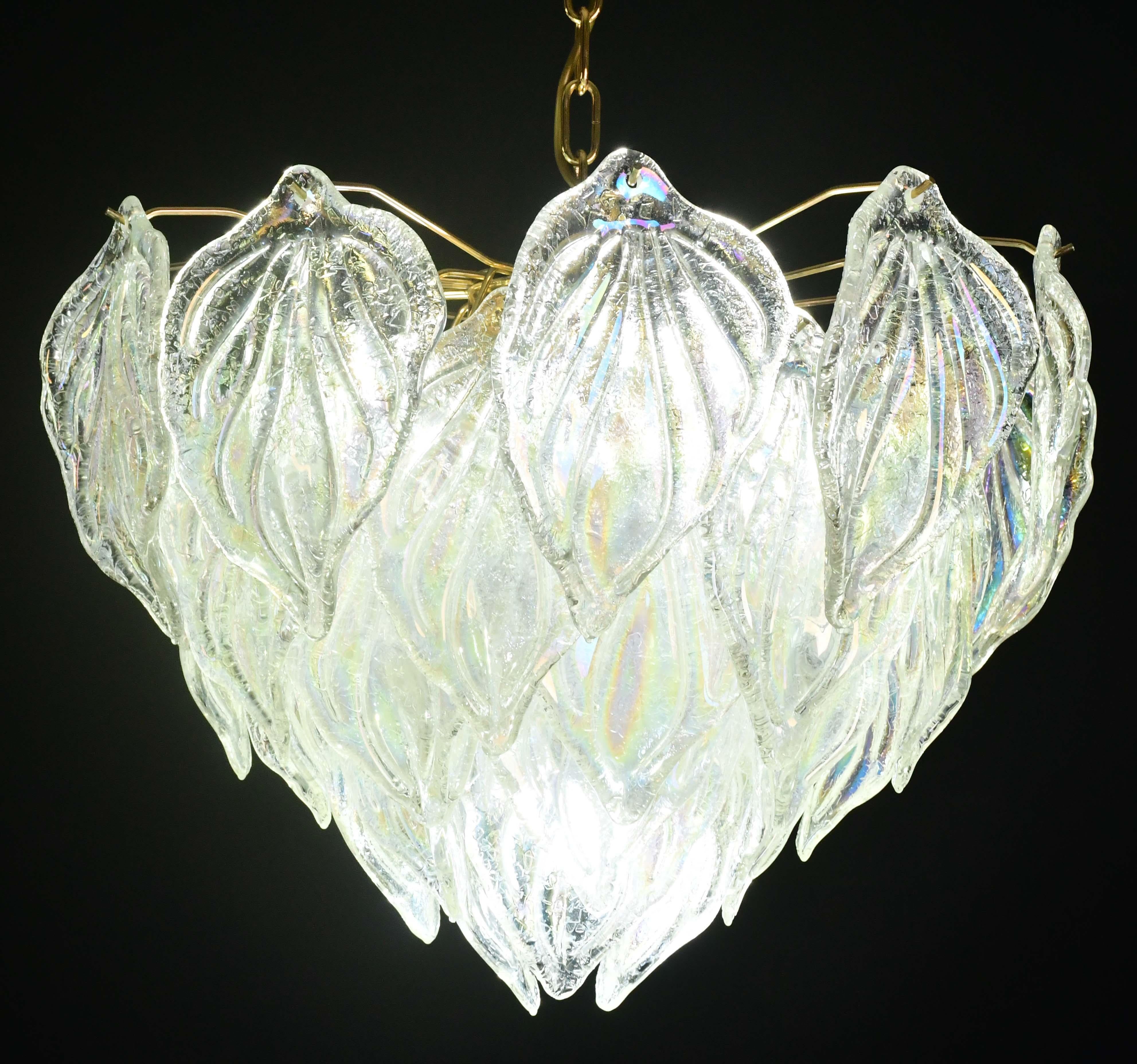 Stupendo lampadario in vetro di Murano con decine di foglie di graniglia in vetro trasparente iridescente. Questo vetro assume i colori dell'arcobaleno quando viene illuminato.
Il lampadario misura 95 centimetri con la catena, 55 centimetri senza