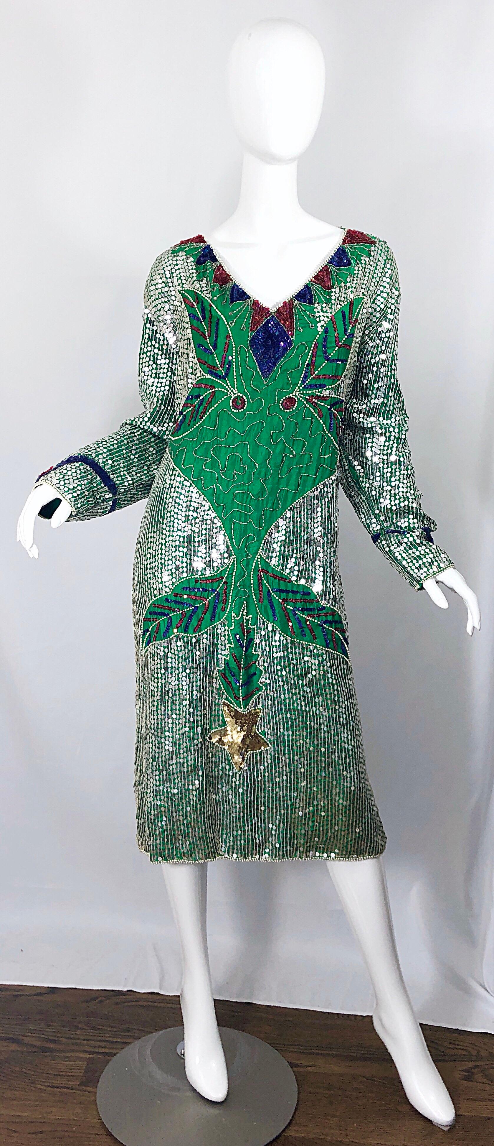 Amazing late 1970s kelly green sequined and beaded long sleeve silk dress! Features a kelly green silk backdrop. Thousands of hand-sewn sequins and beads throughout. Vibrant colors of blue, silver, red, and gold throughout. 
Simply slips over the
